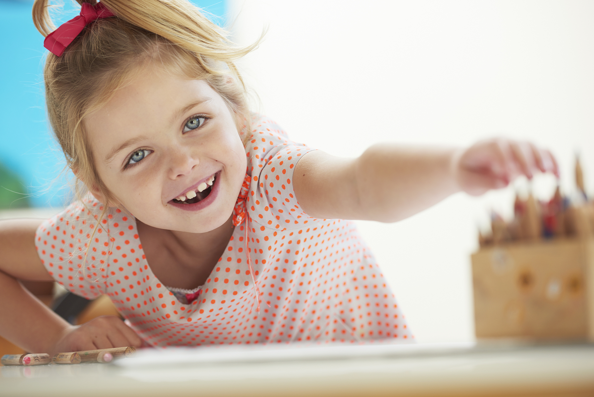 young girl reaching for pencils