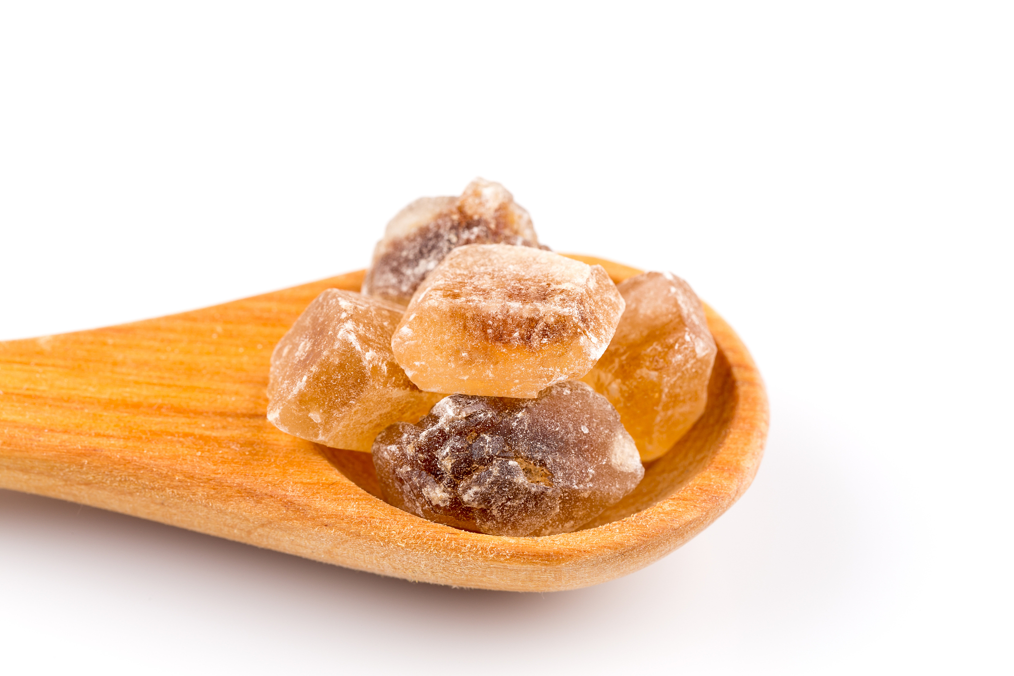 brown caramelized sugar in a wooden spoon on a white background