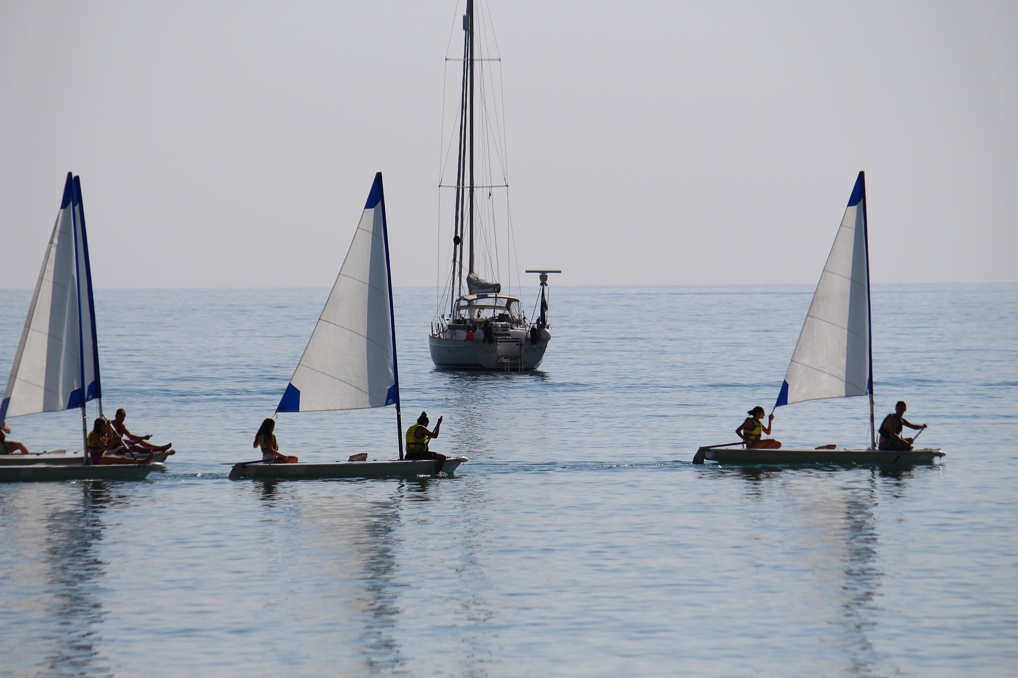 people sailing boat in sea against clear sky