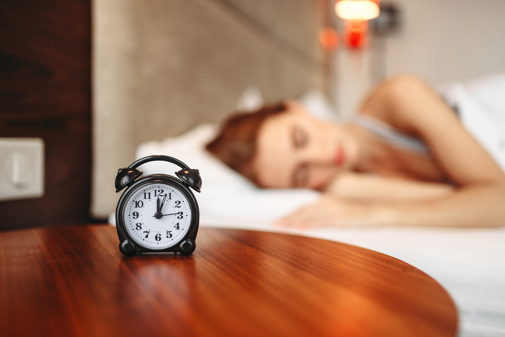 alarm clock, woman covering her ears with pillow