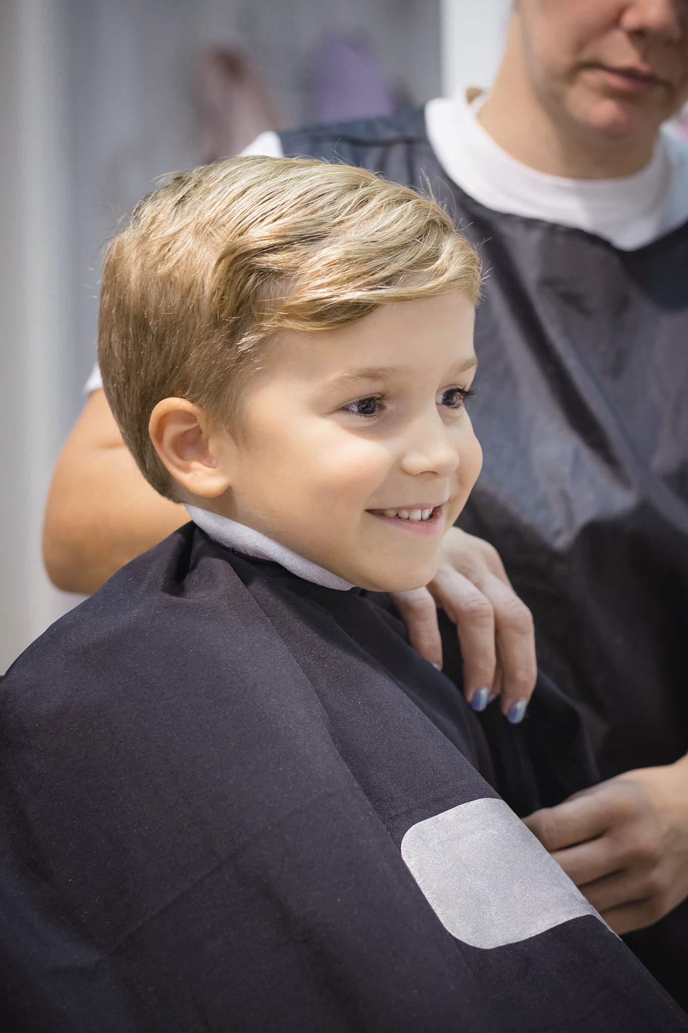 smiling boy sitting at barber shop