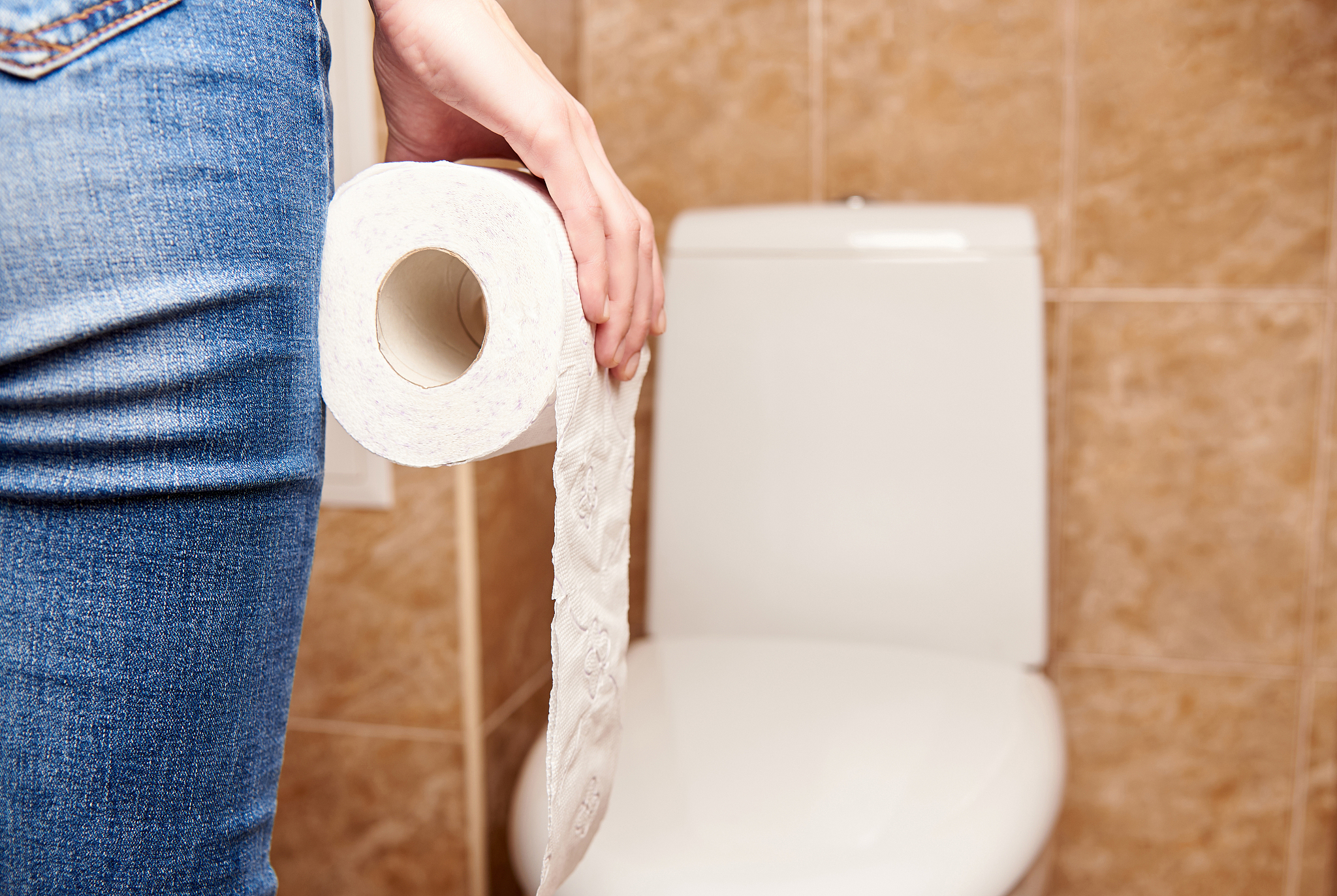 man with a roll of toilet paper on the background of a blurred t
