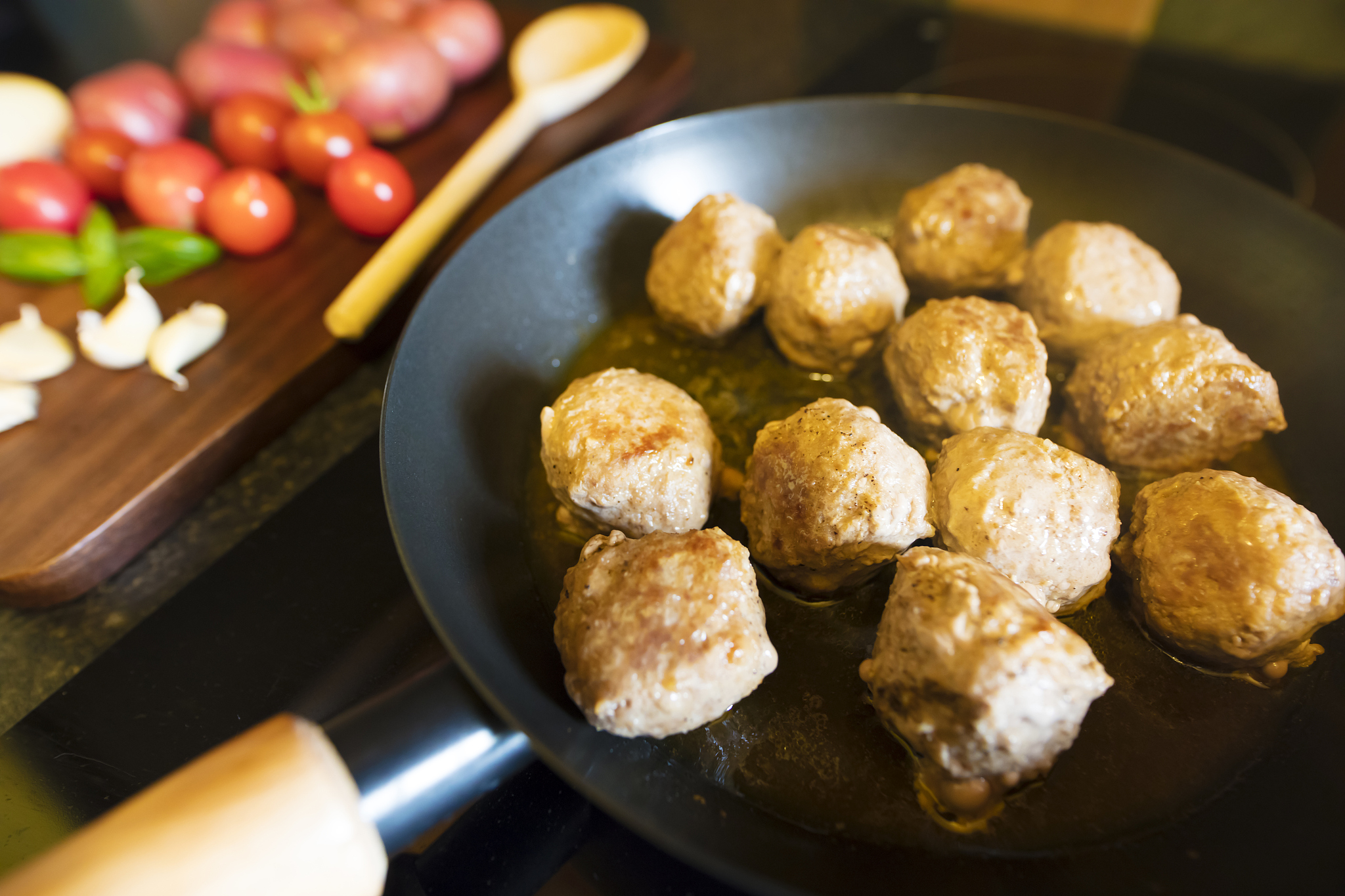 close-up of meatballs in frying pan on hot electric hob