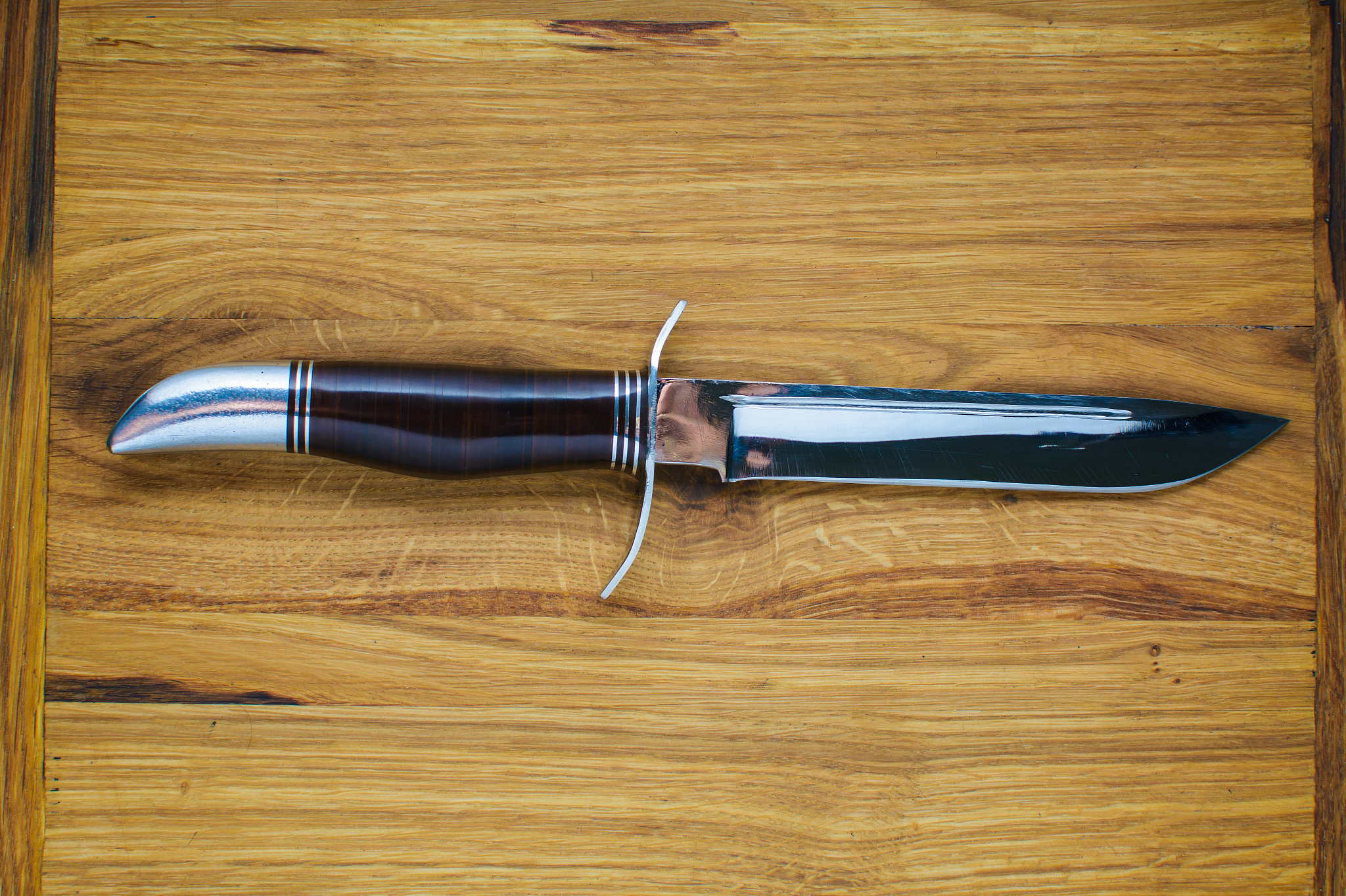 a beautiful mirror knife for hunting lies on a wooden cutting bo