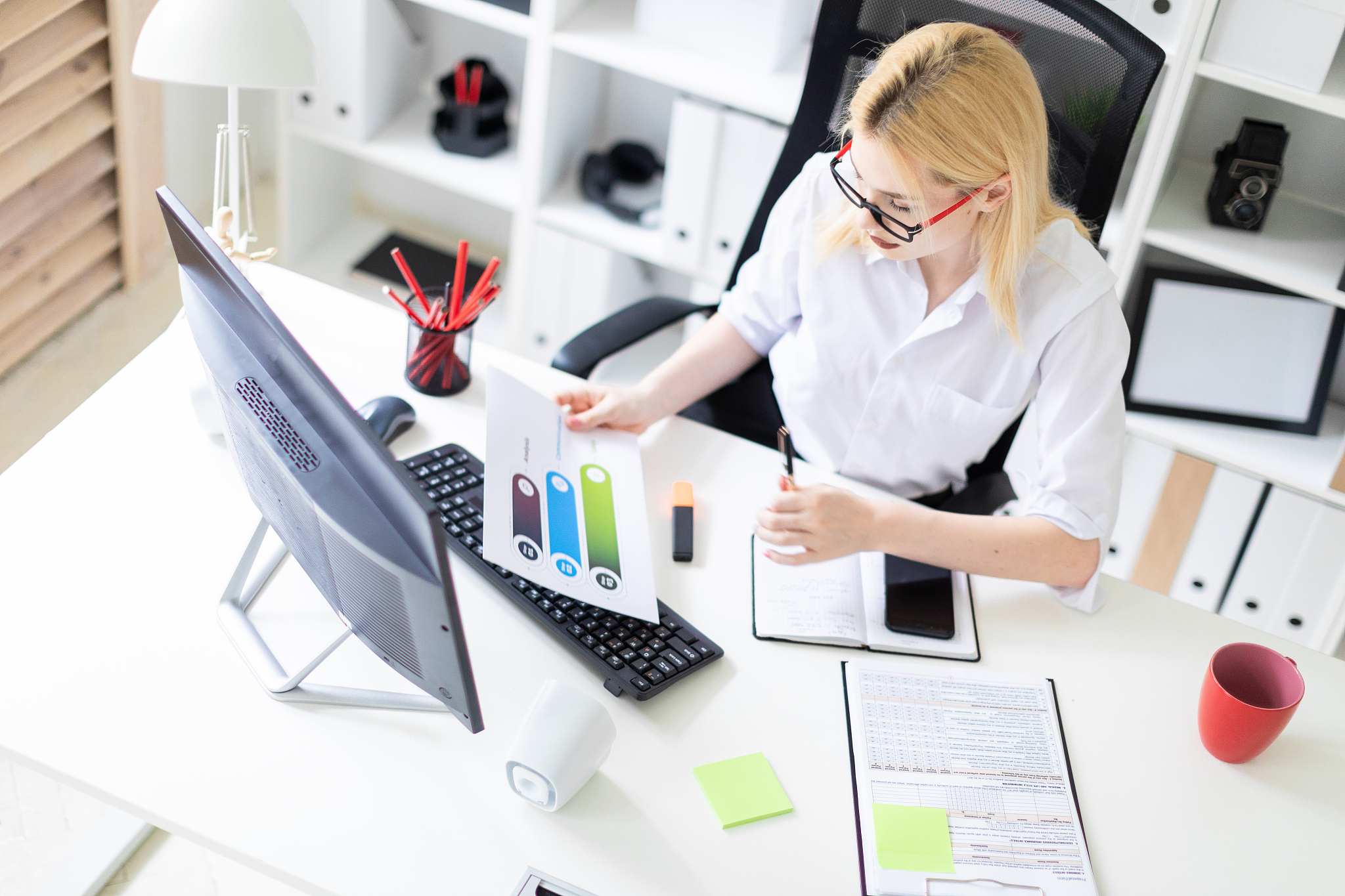 a young girl working in the office with a computer and documents