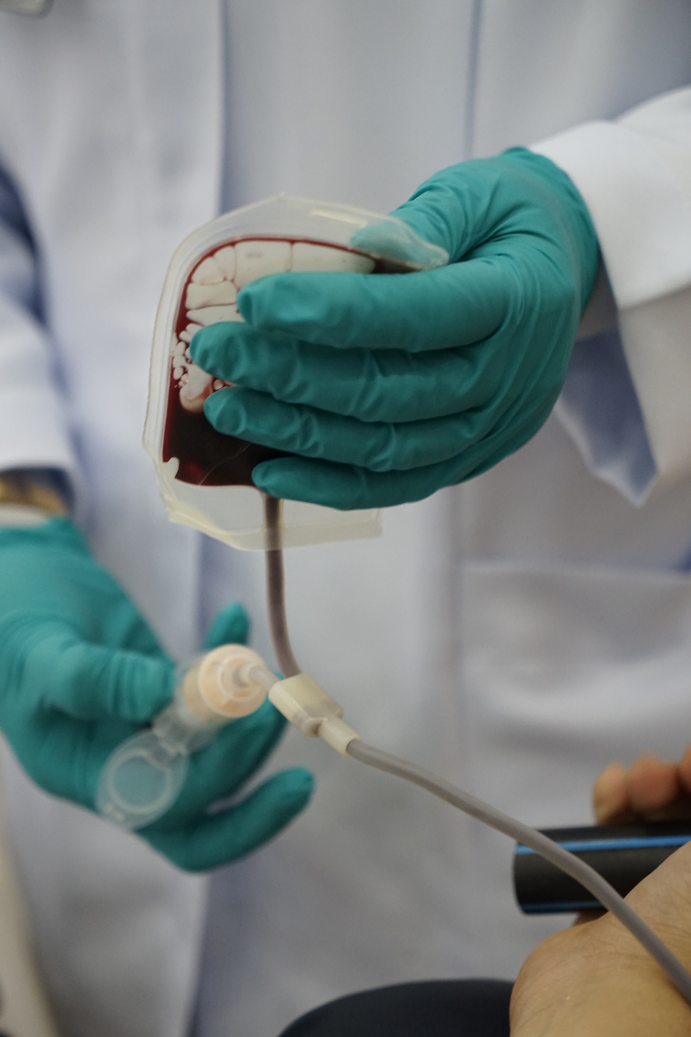 midsection of doctor holding human blood in bag at hospital ward