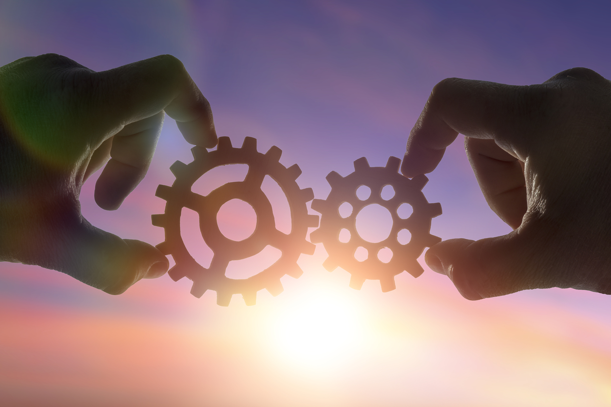 hands businessman holding gears on the background of the sky in 