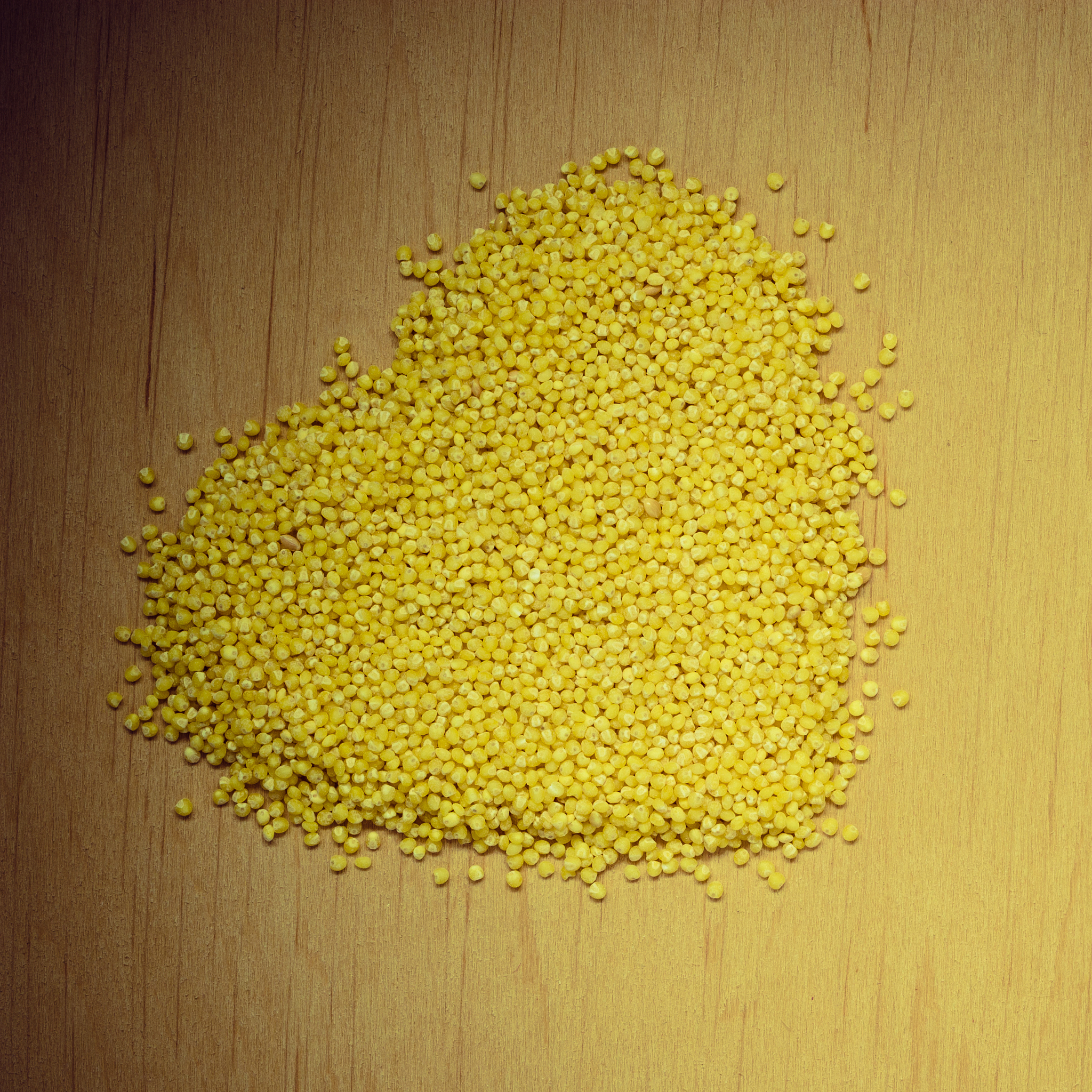 millet groats heart shaped on wooden surface.