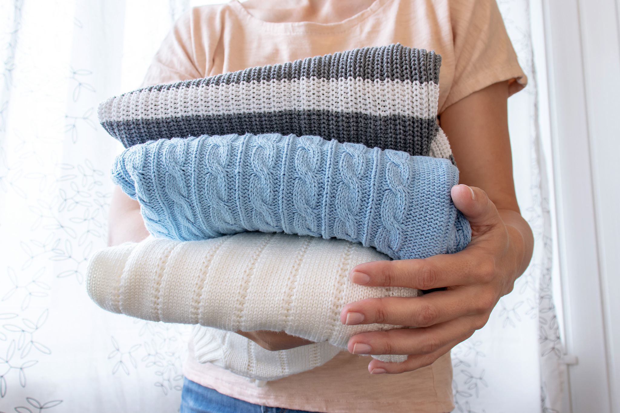 woman, housewife holding a stack of clothes in hands close up