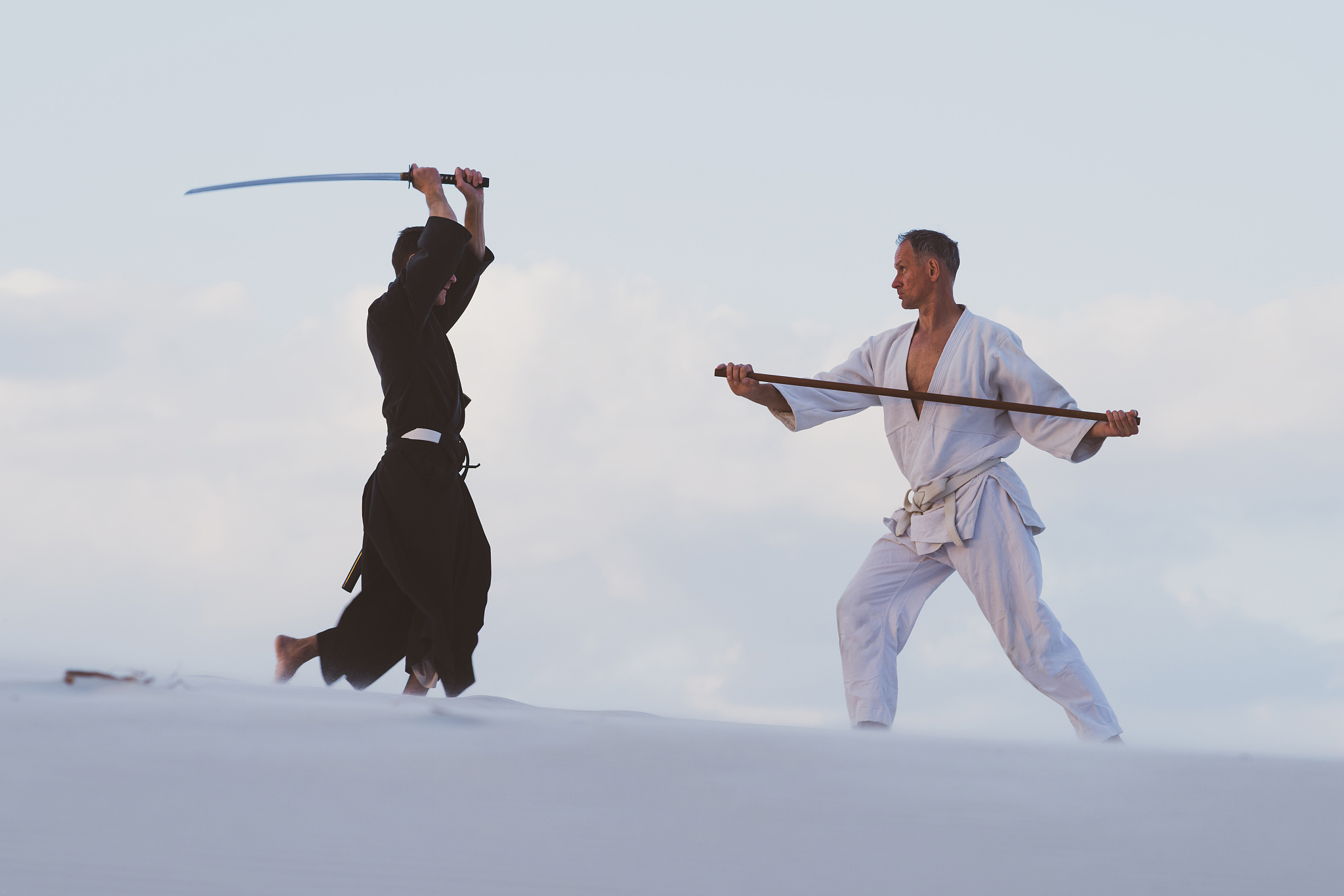 two men practicing japanese martial arts in desert