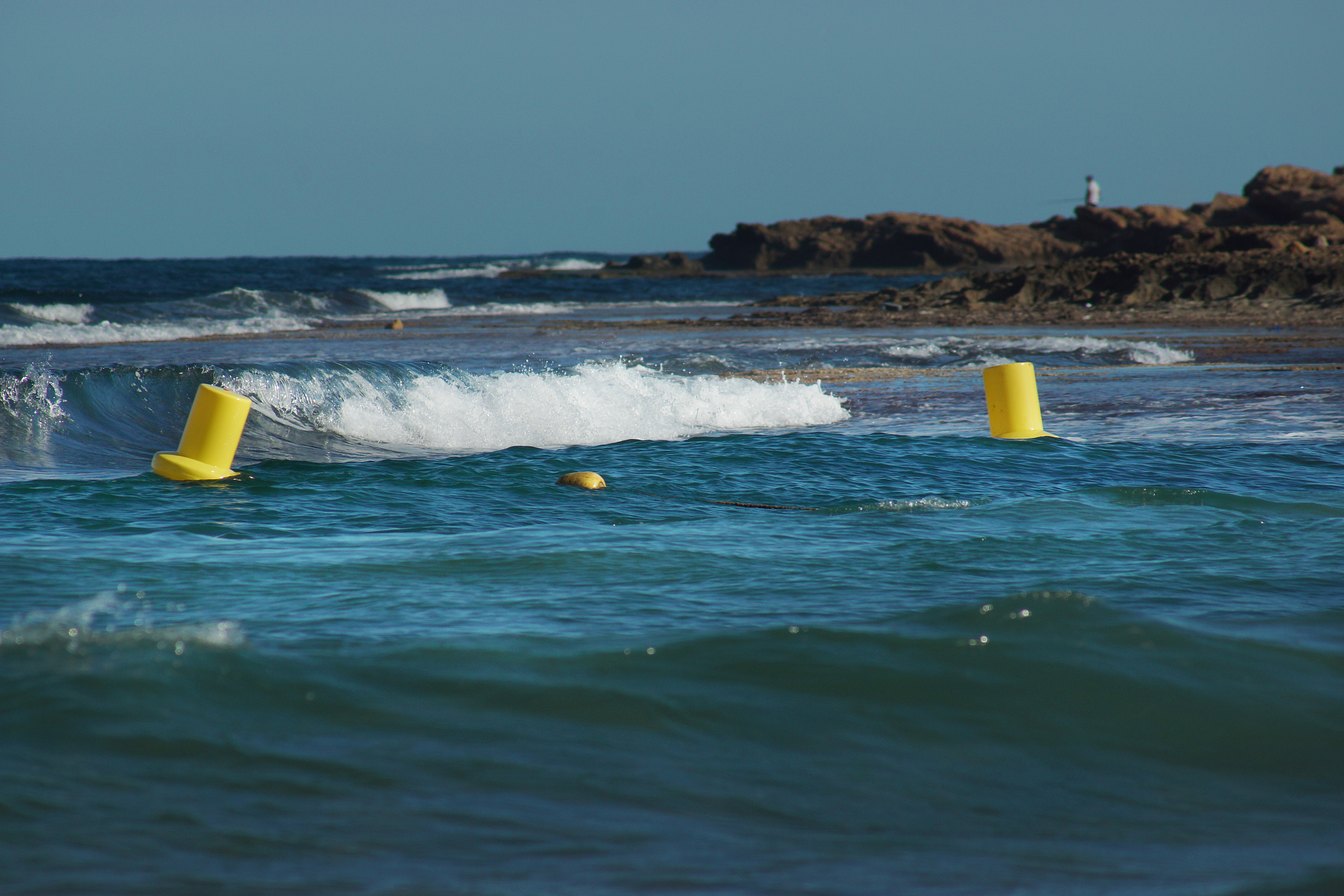sea wave striking the shore, yellow buoys