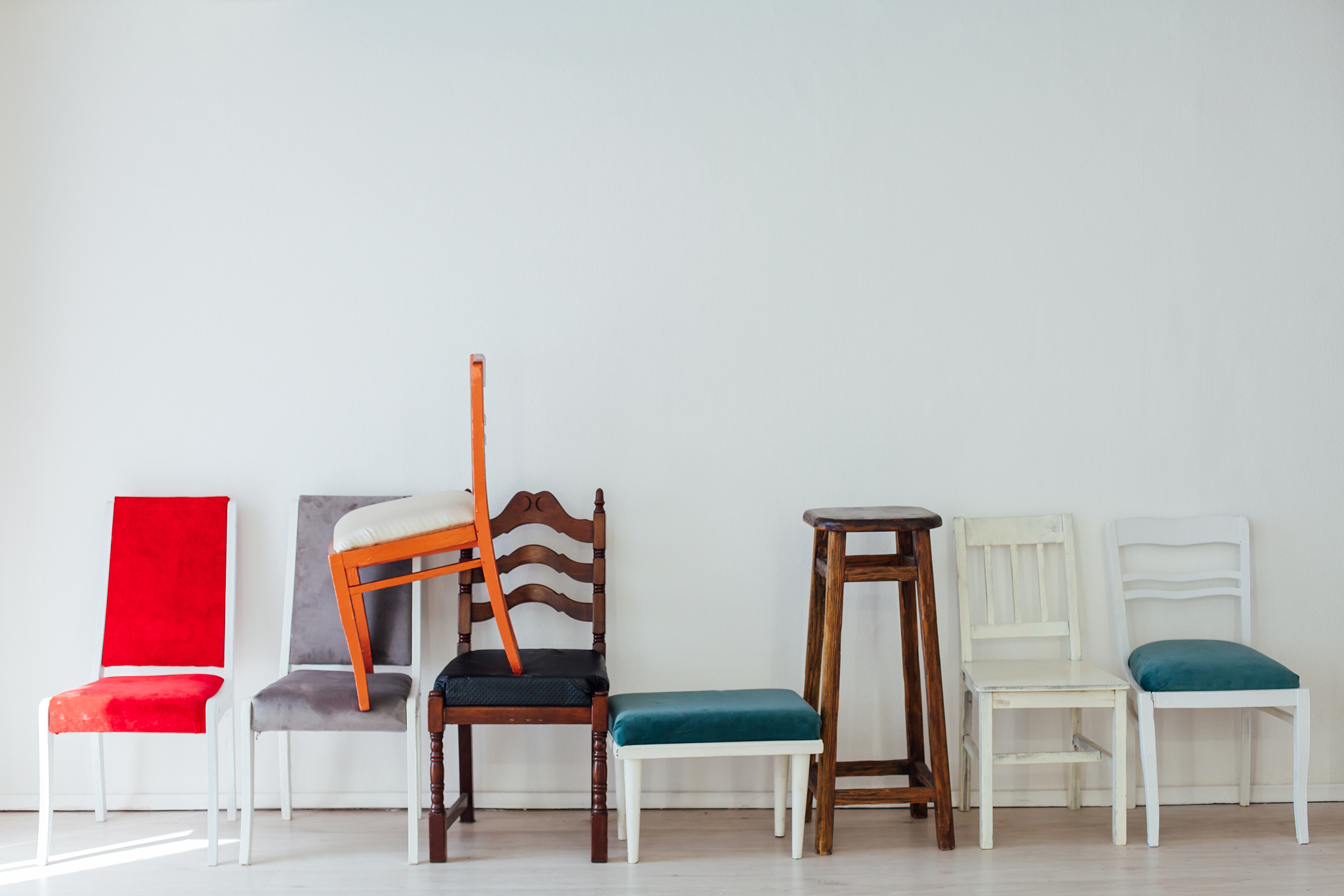 lots of different chairs in the empty white interior room