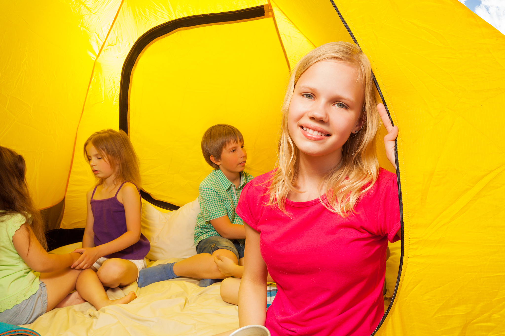 four kids sit in a tent