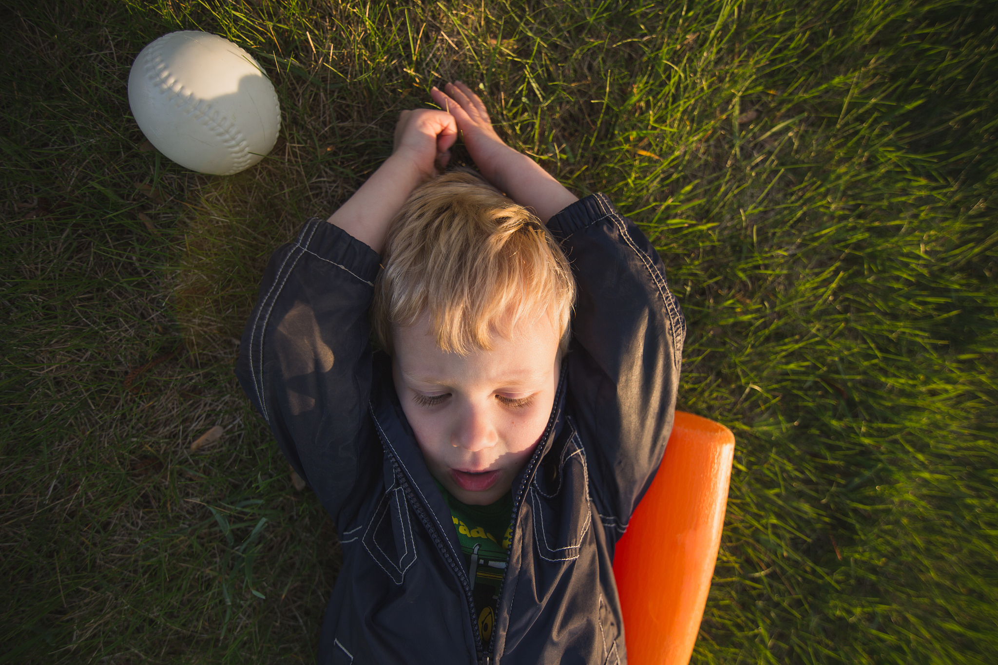 boy laying by bat and ball