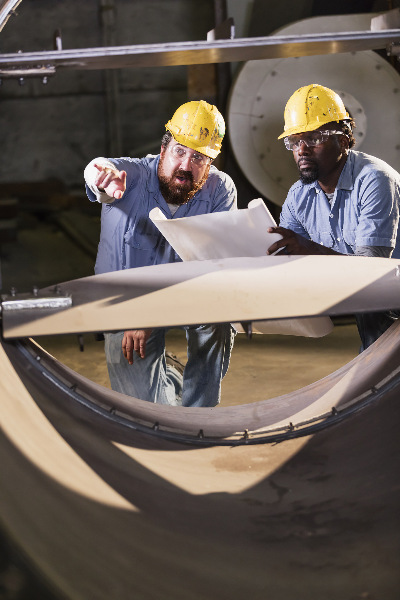 workers in factory inspecting metal object