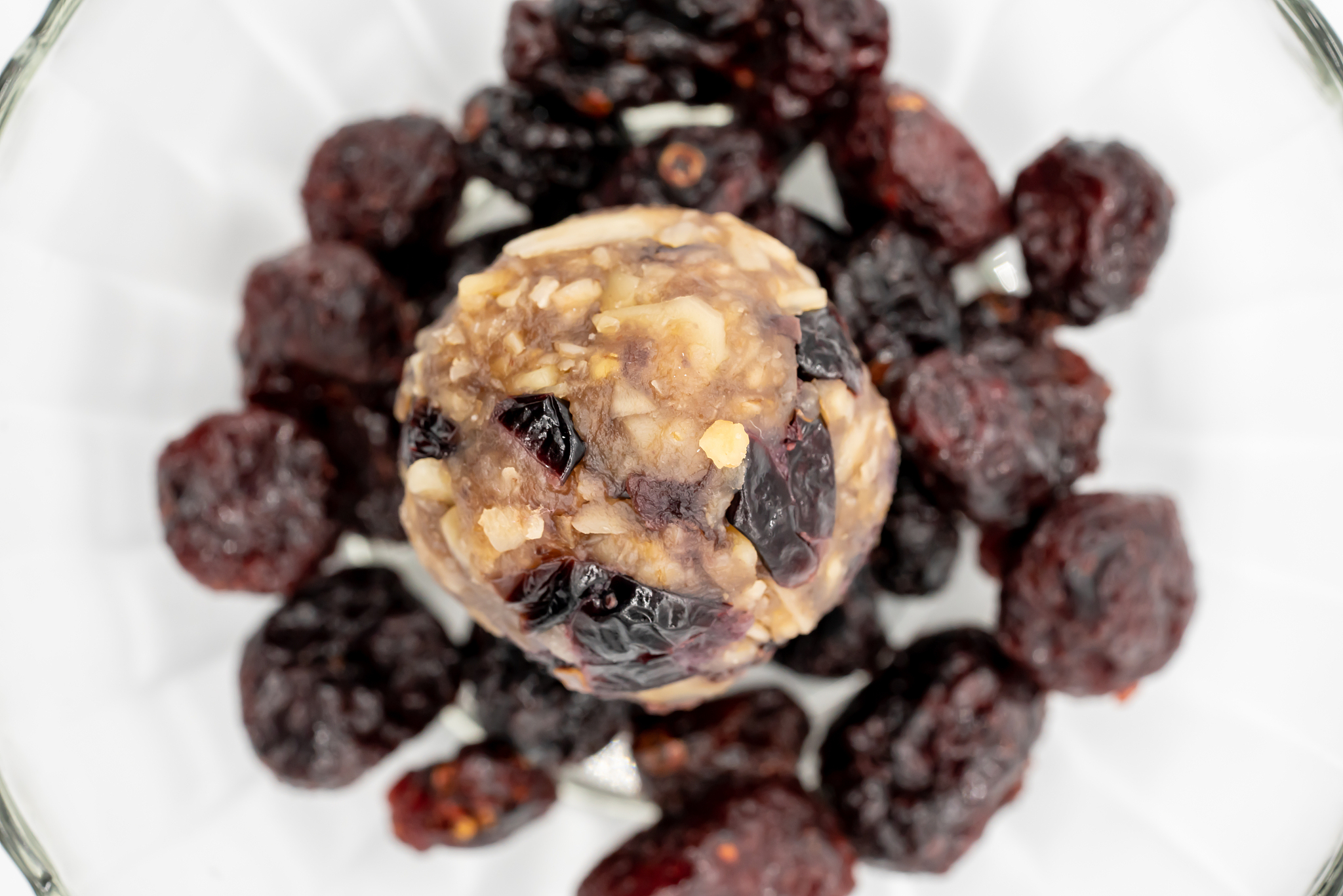 close up healthy energy ball among dried berries in glass bowl i
