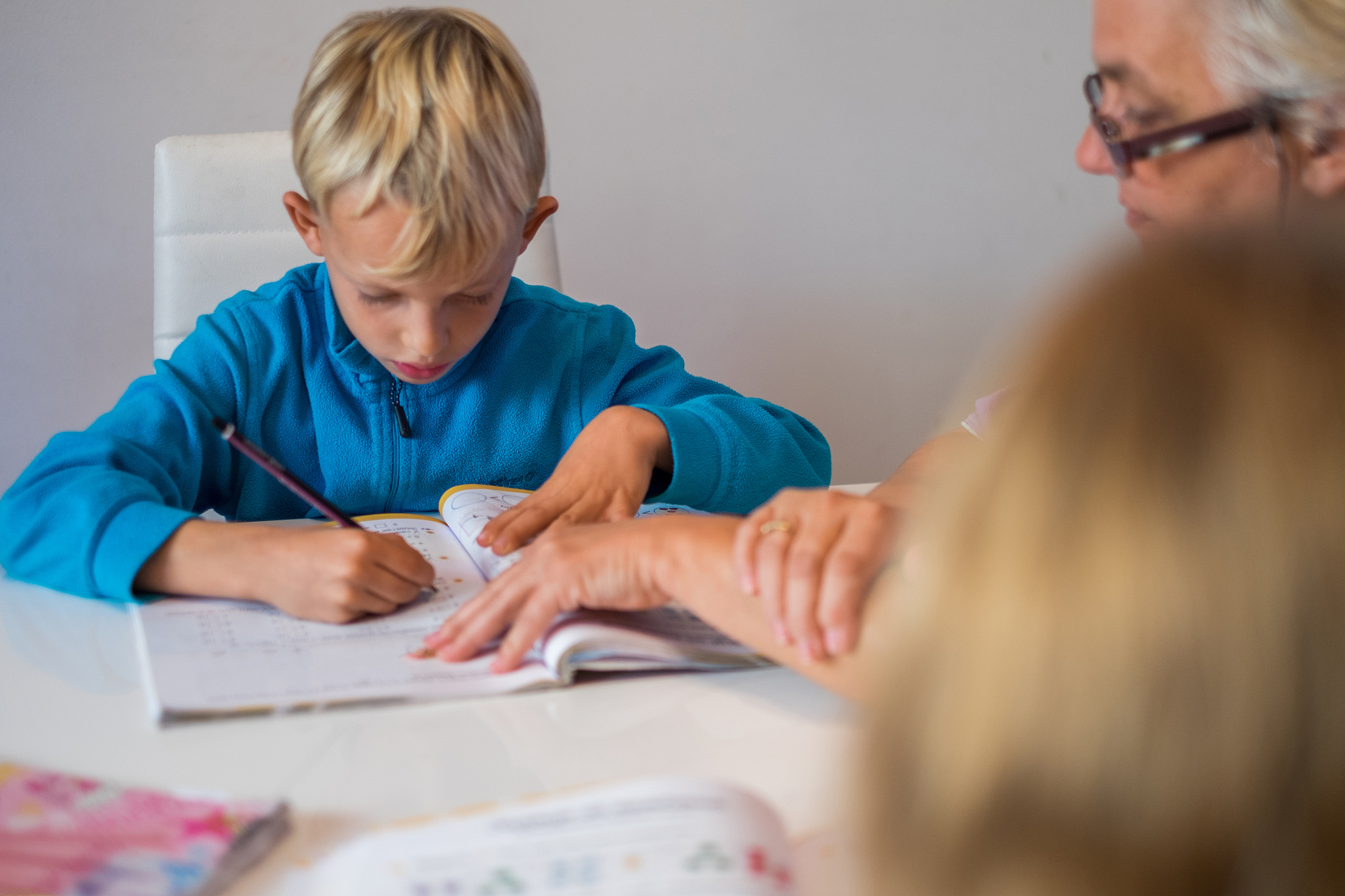 boy writing homework with grandmother help
