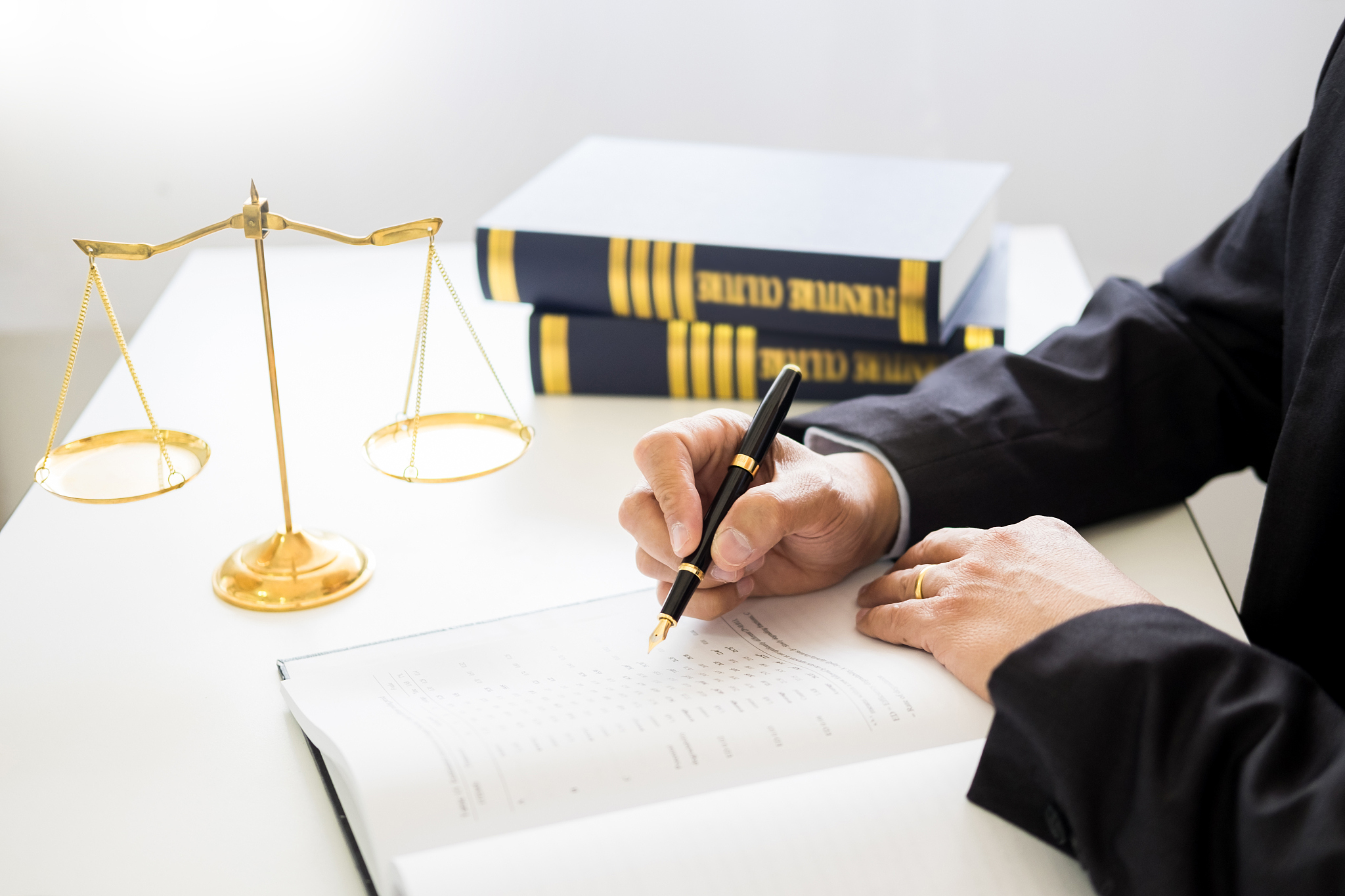 midsection of lawyer writing on book at office