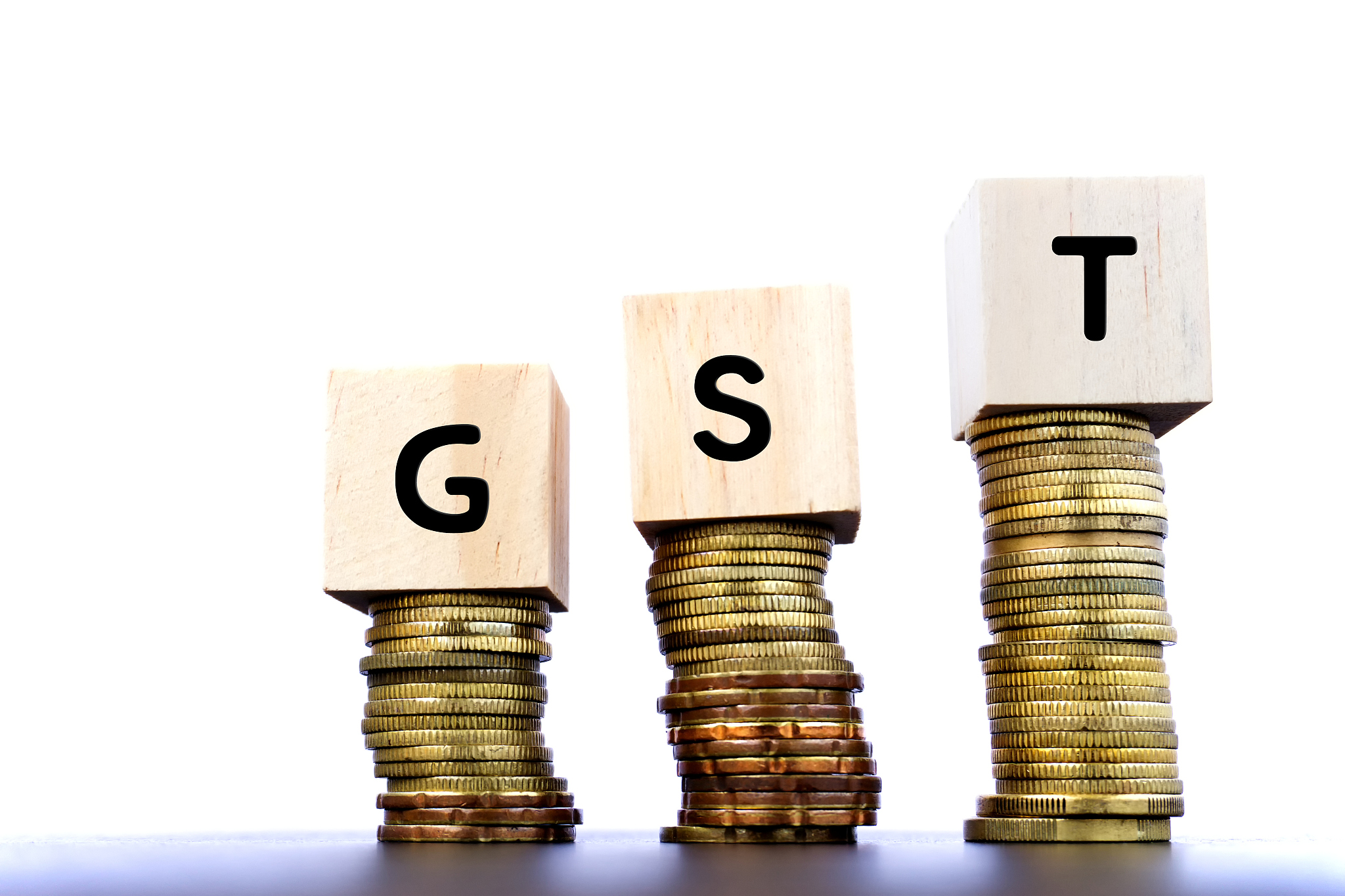 gst word on wood block on top of coins stack