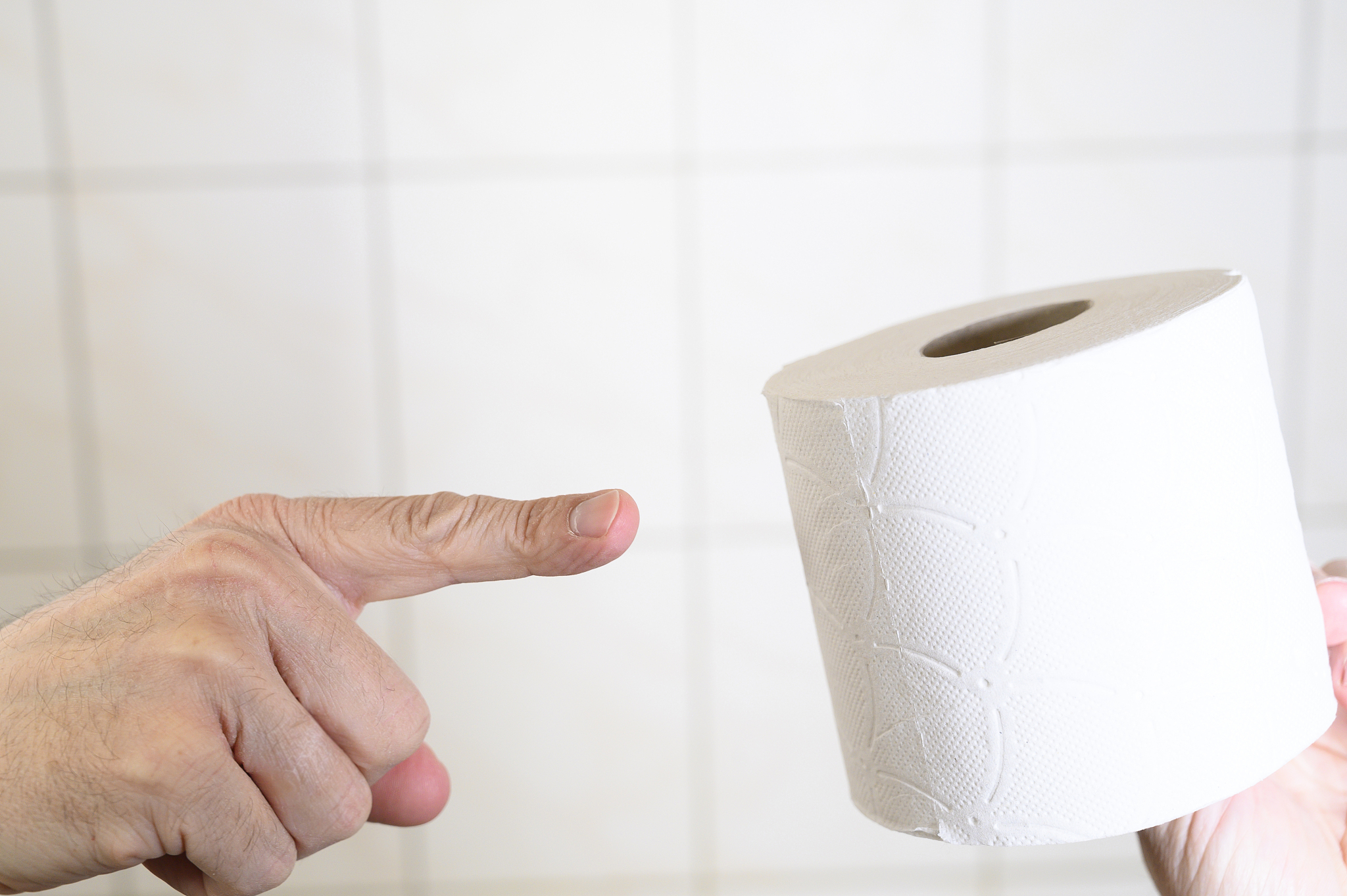 man's hand pointing out with his index finger a toilet paper in 