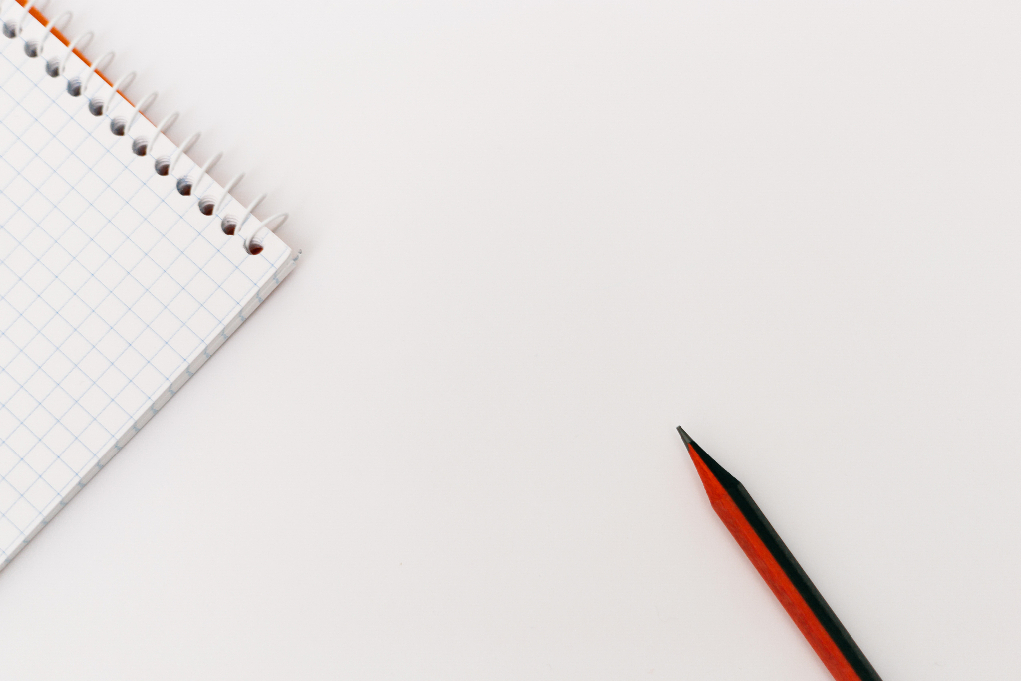 top view of an open spiral blank notepad with a pencil on a whit