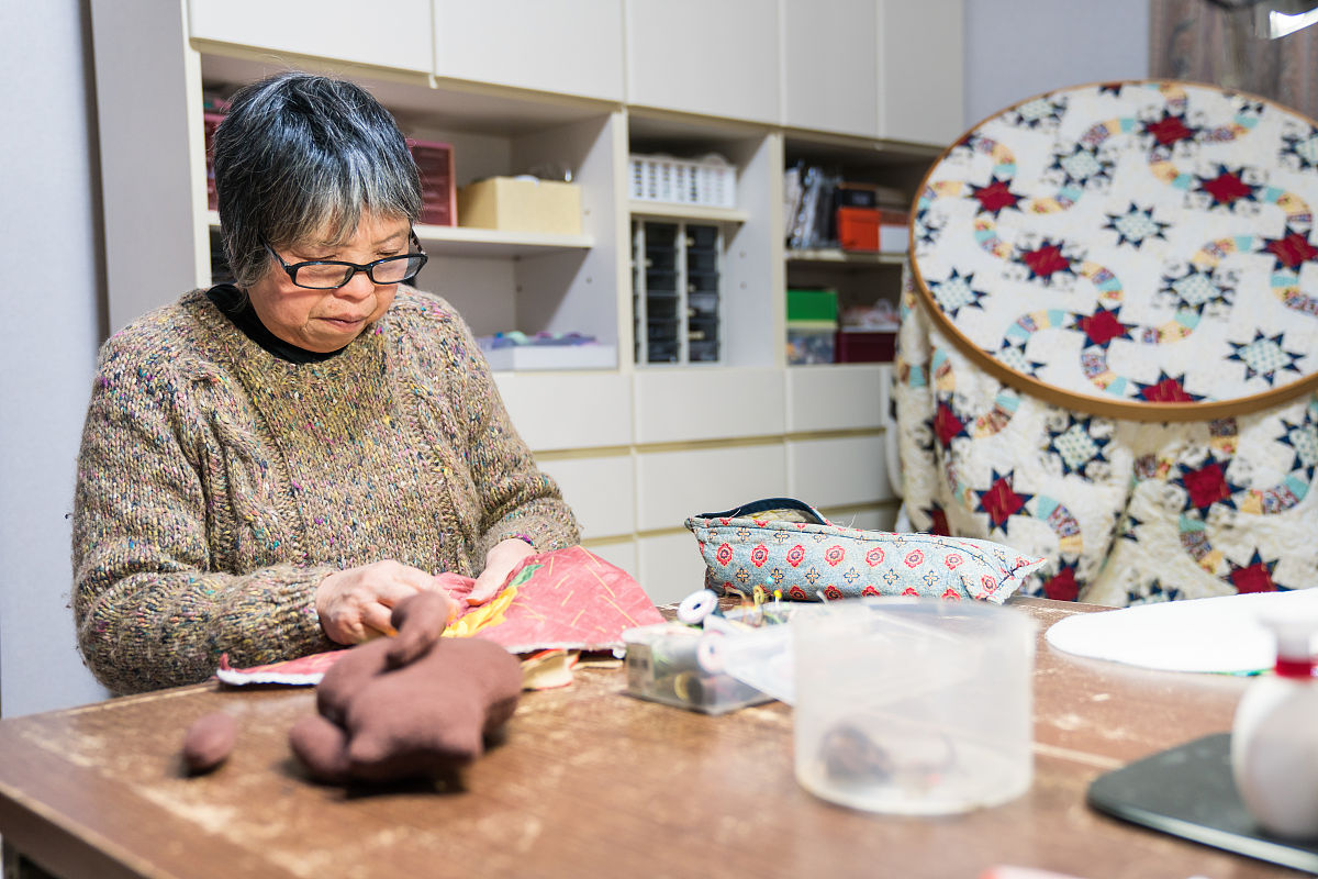 一位年长妇女在她的家中缝纫和制作工艺品