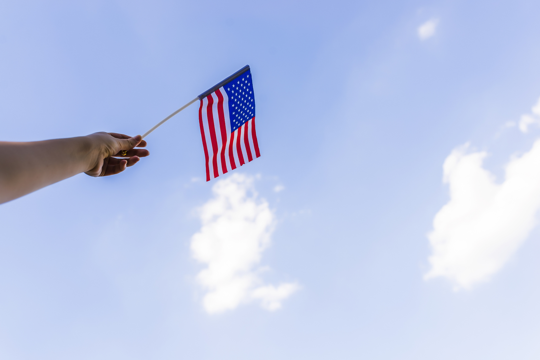 woman's hand waving american flag outside on fourth of july