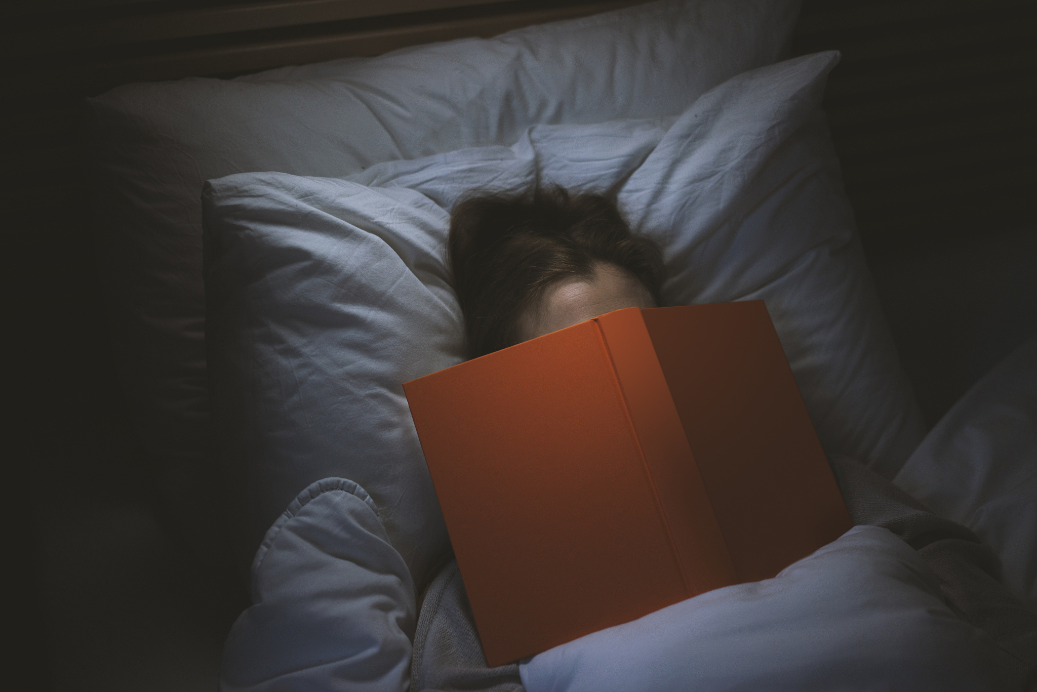 woman fall asleep reading a book in bed at night