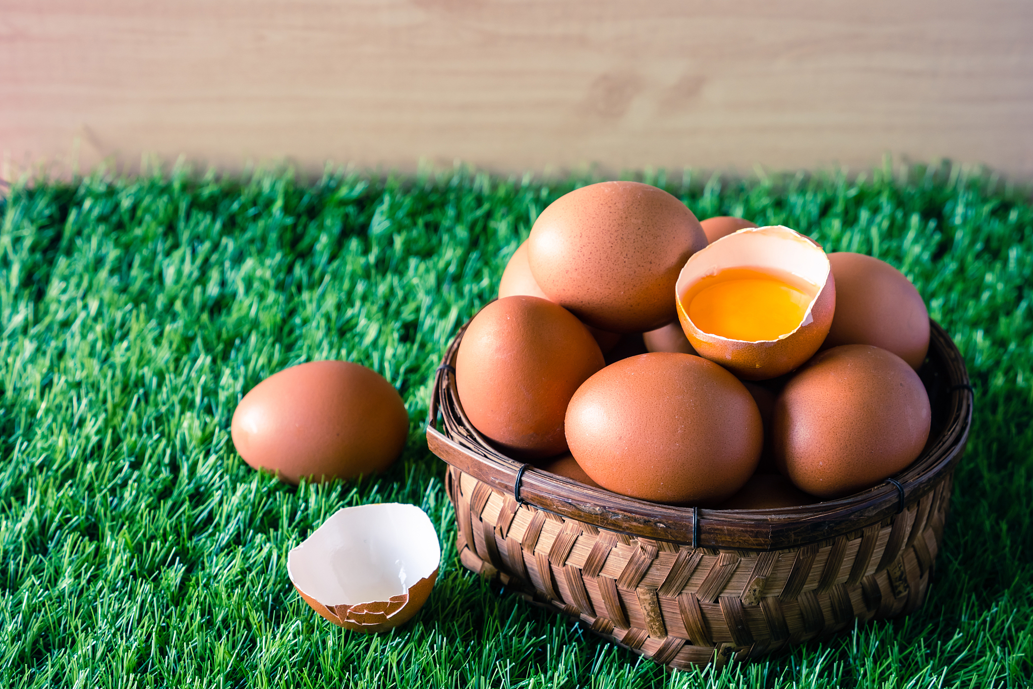 eggs in wooden basket on green grass.