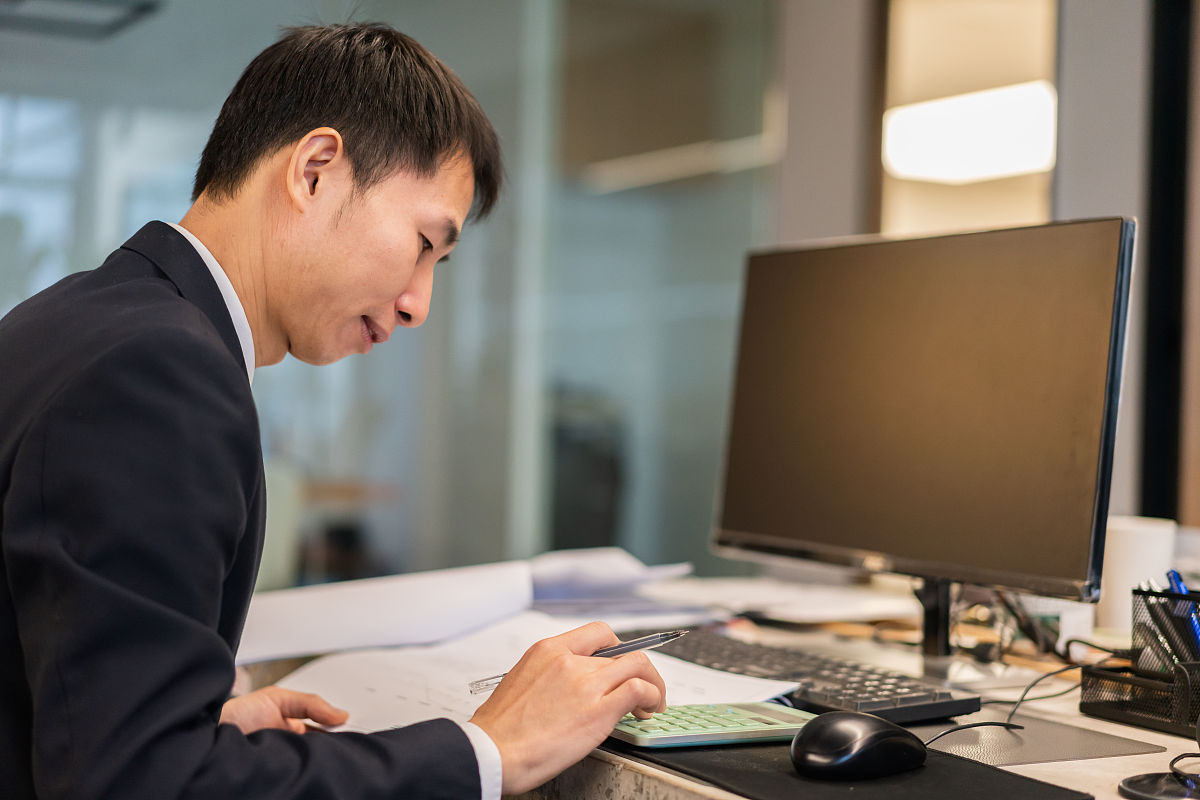 一个人在办公室工作台上用计算器进行计算