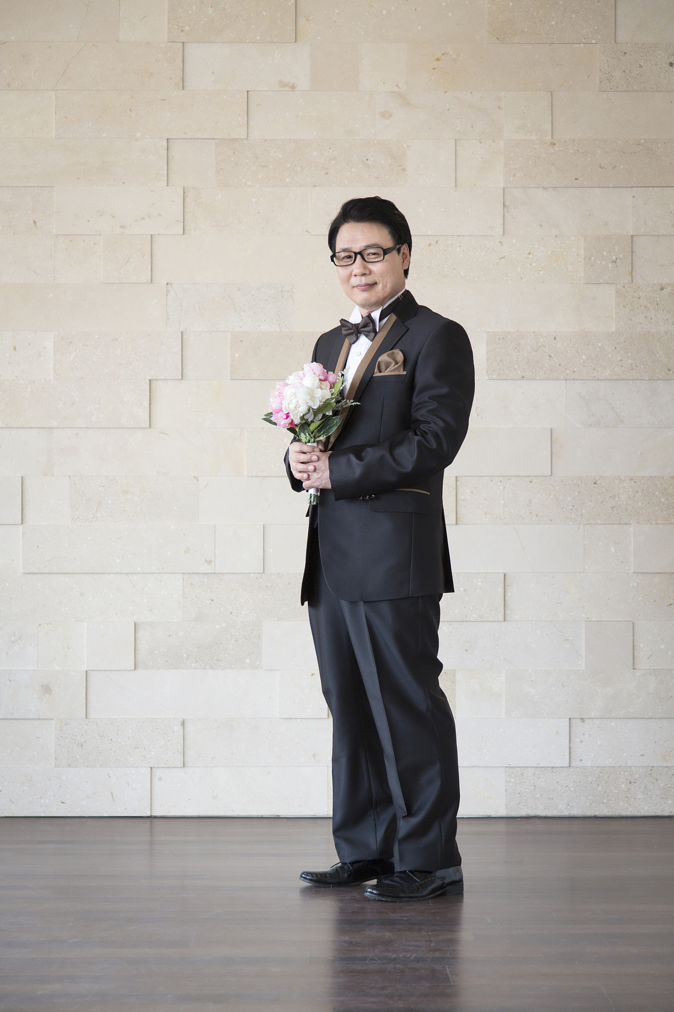 photography of mature man standing holding flower