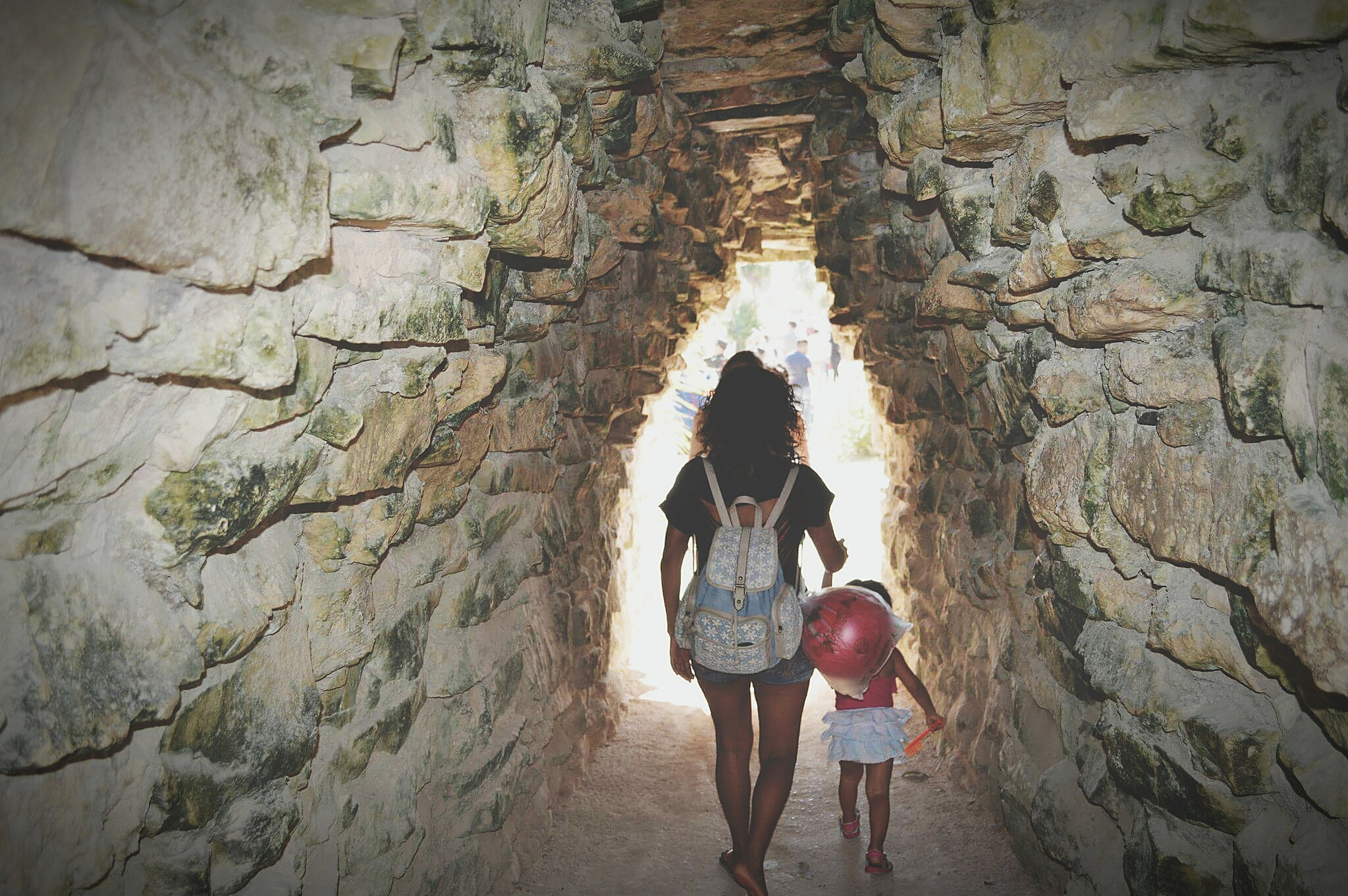 woman with girl walking in cave