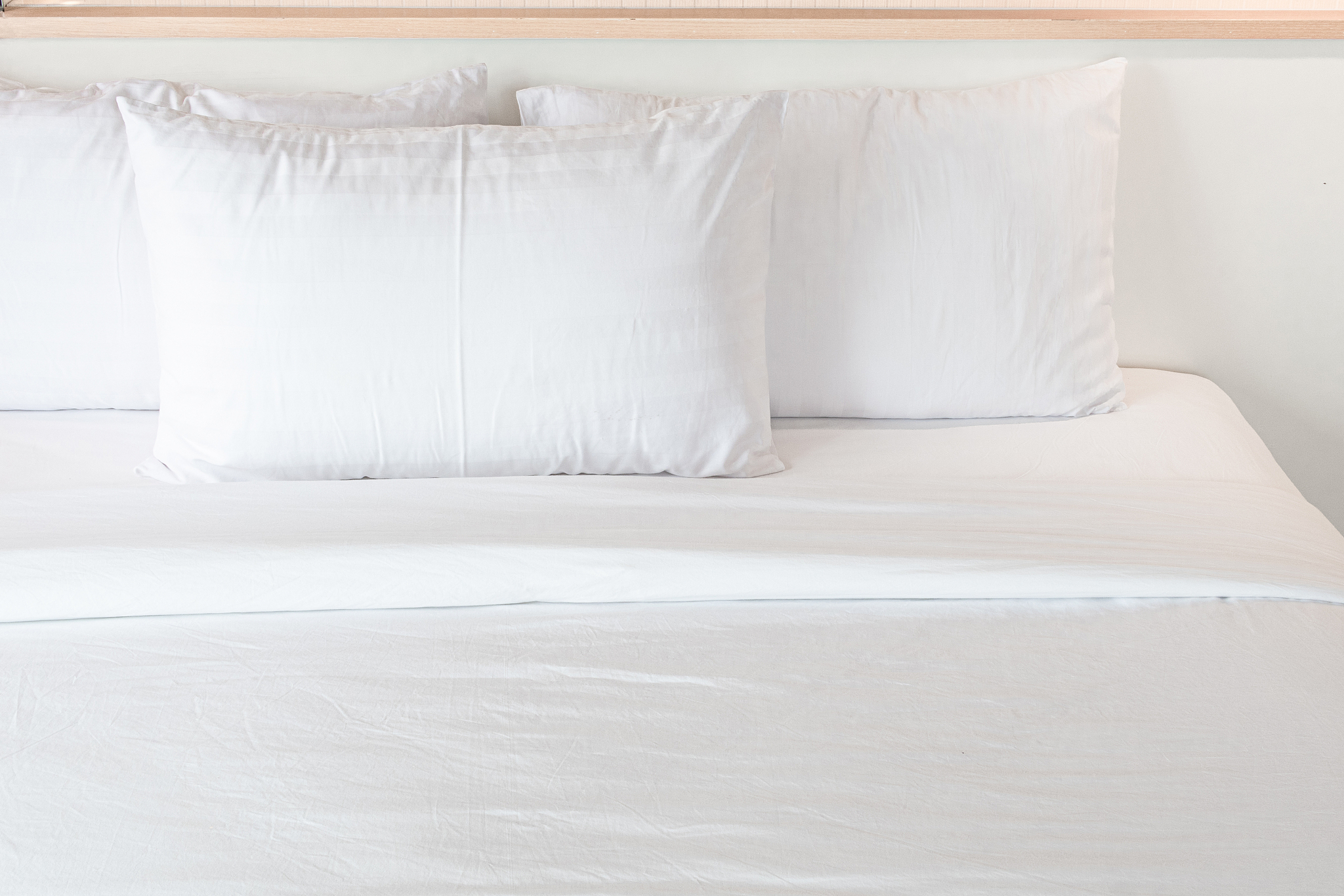 three white pillows neatly arranged on the white bed. hotel serv