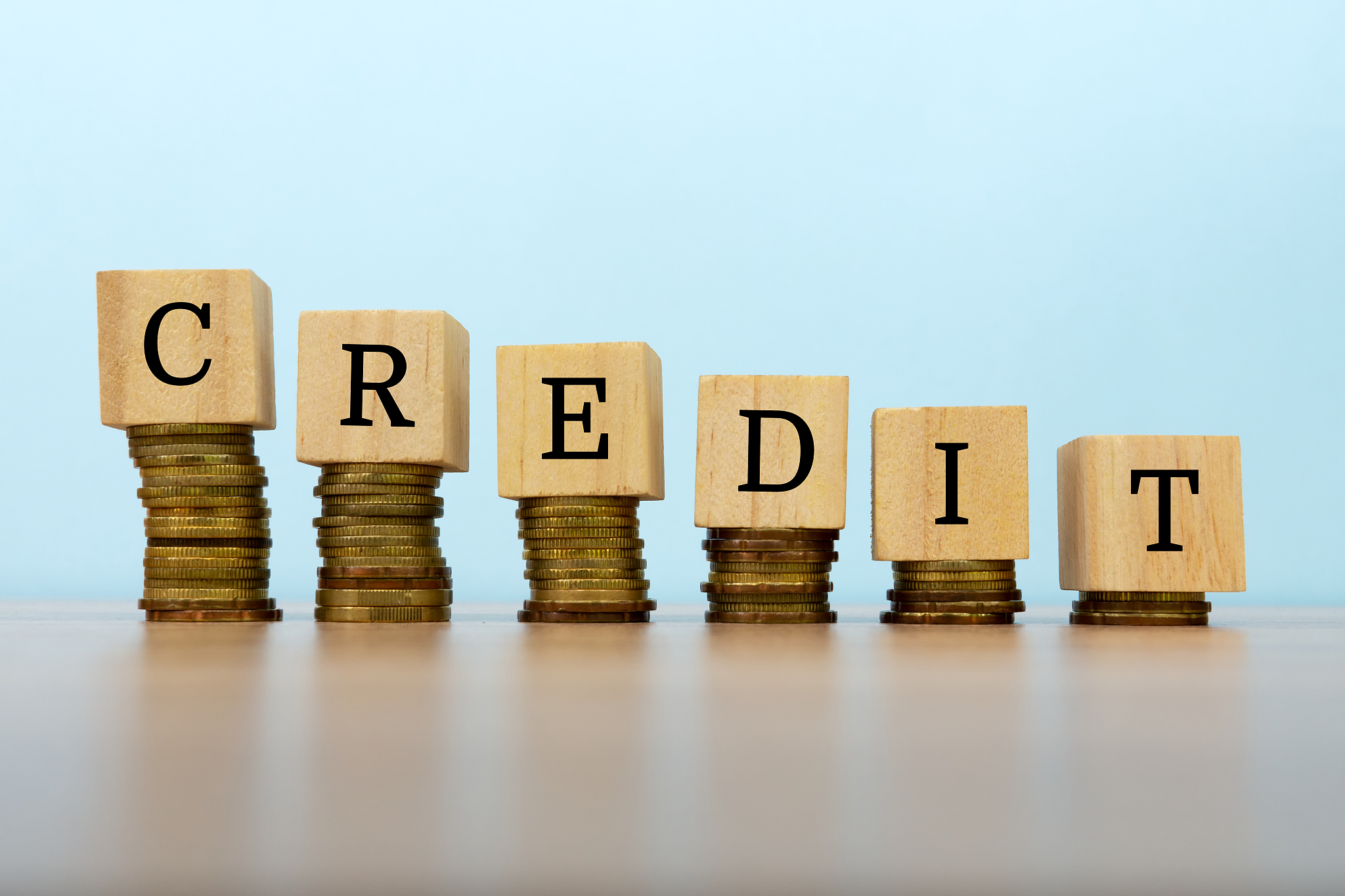 credit text written on wooden block with stacked coins