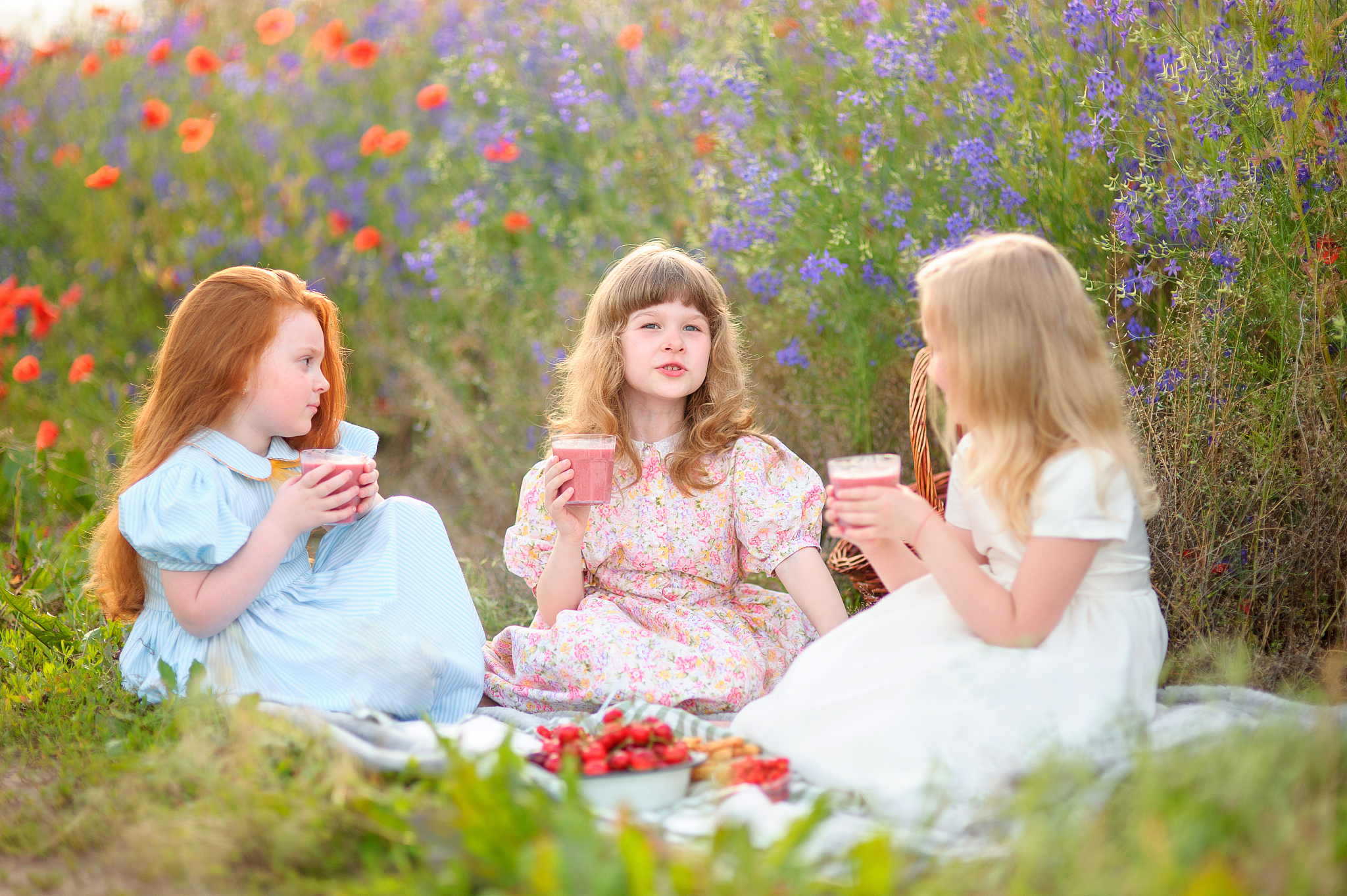 happy children eating strawberry cocktail outdoors in poppy fiel