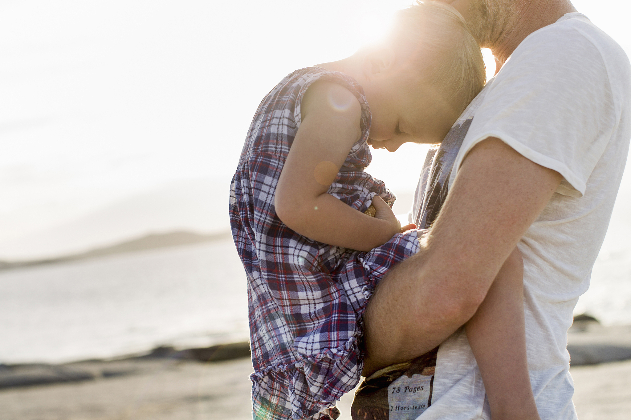 mature man holding his toddler daughter on beach, calvi, corsica