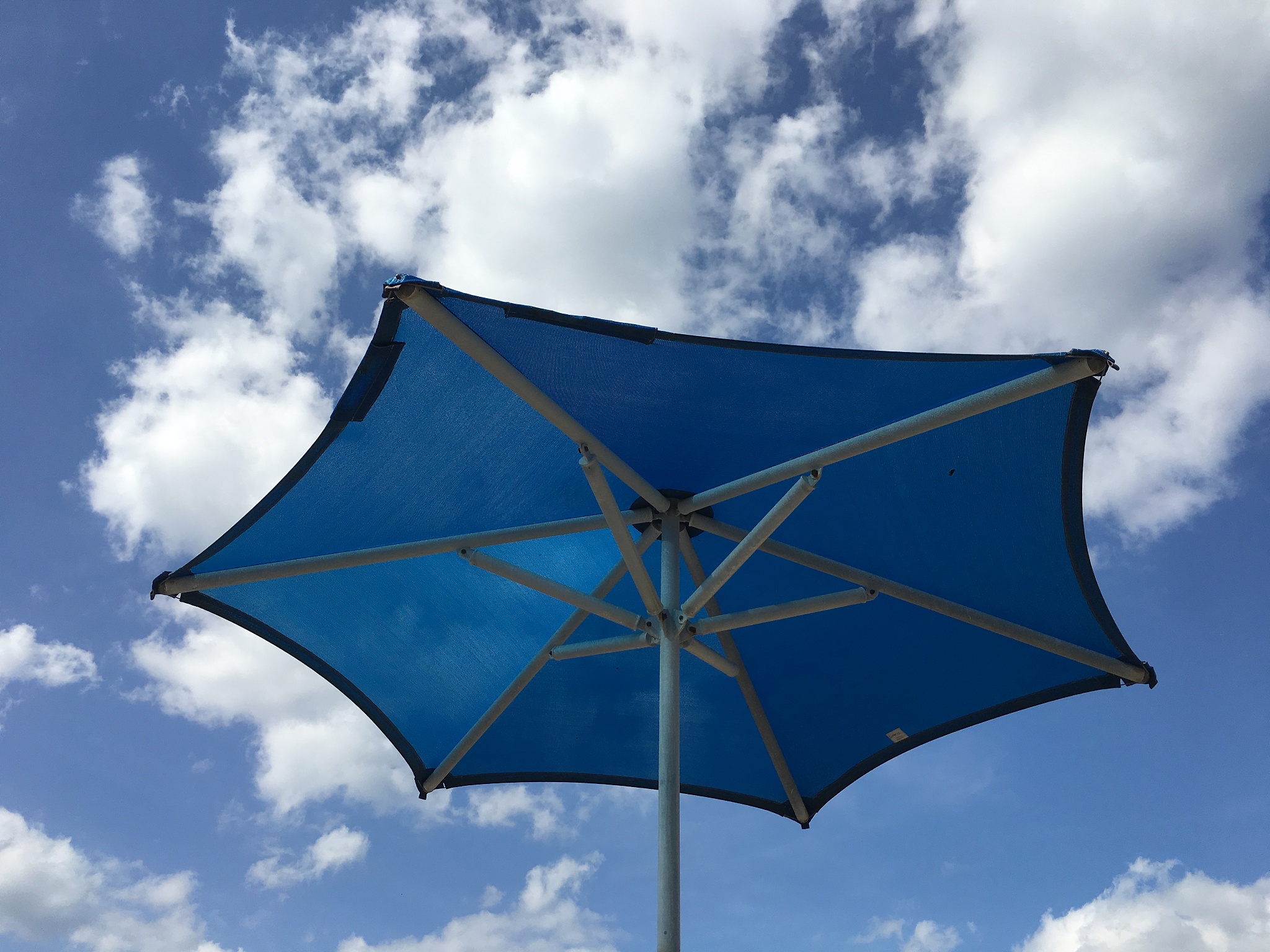bright blue beach umbrella and a bright blue sky with clouds