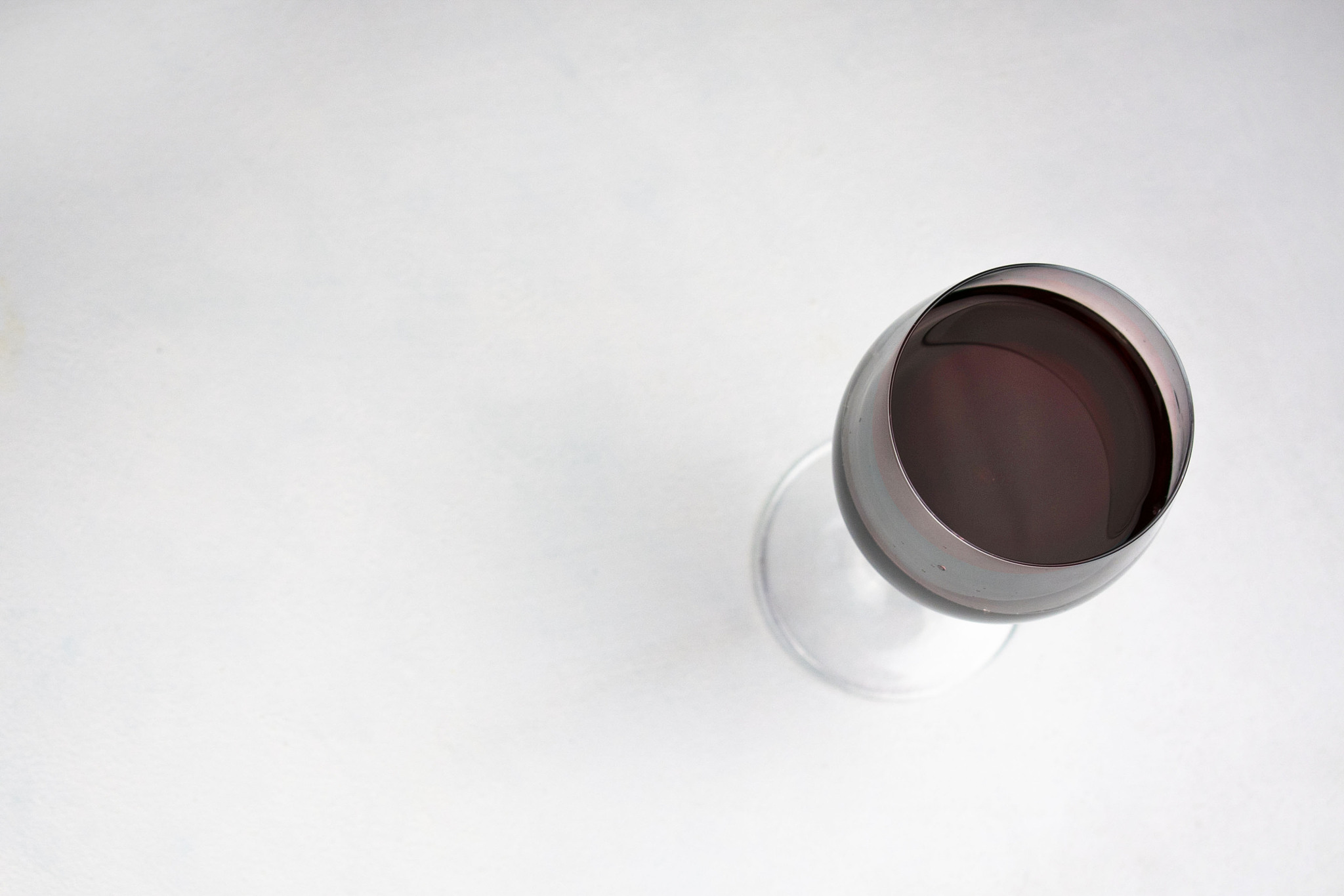 glass with red wine on white table. copy space. top view.