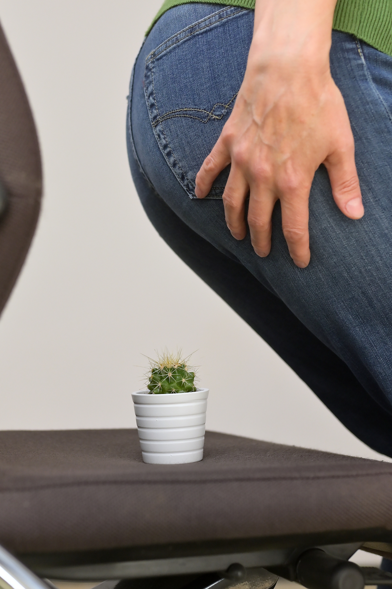 woman suffering from hemorrhoids and thorny cactus on chair