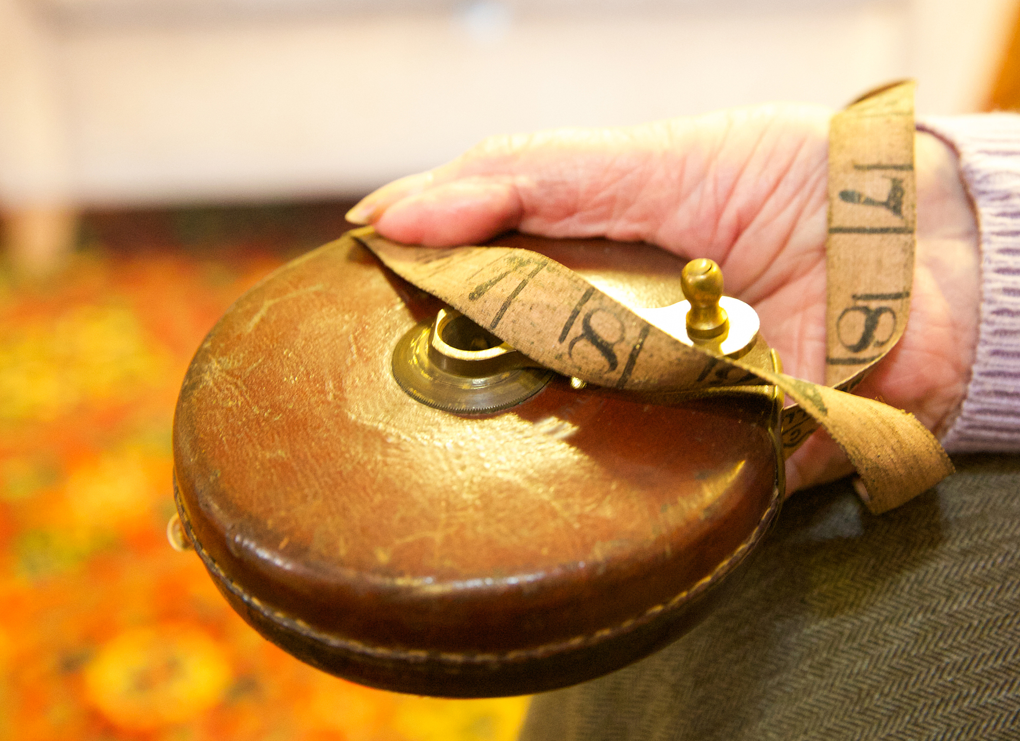 elderly hand holding an old leather imperial extendable tape mea