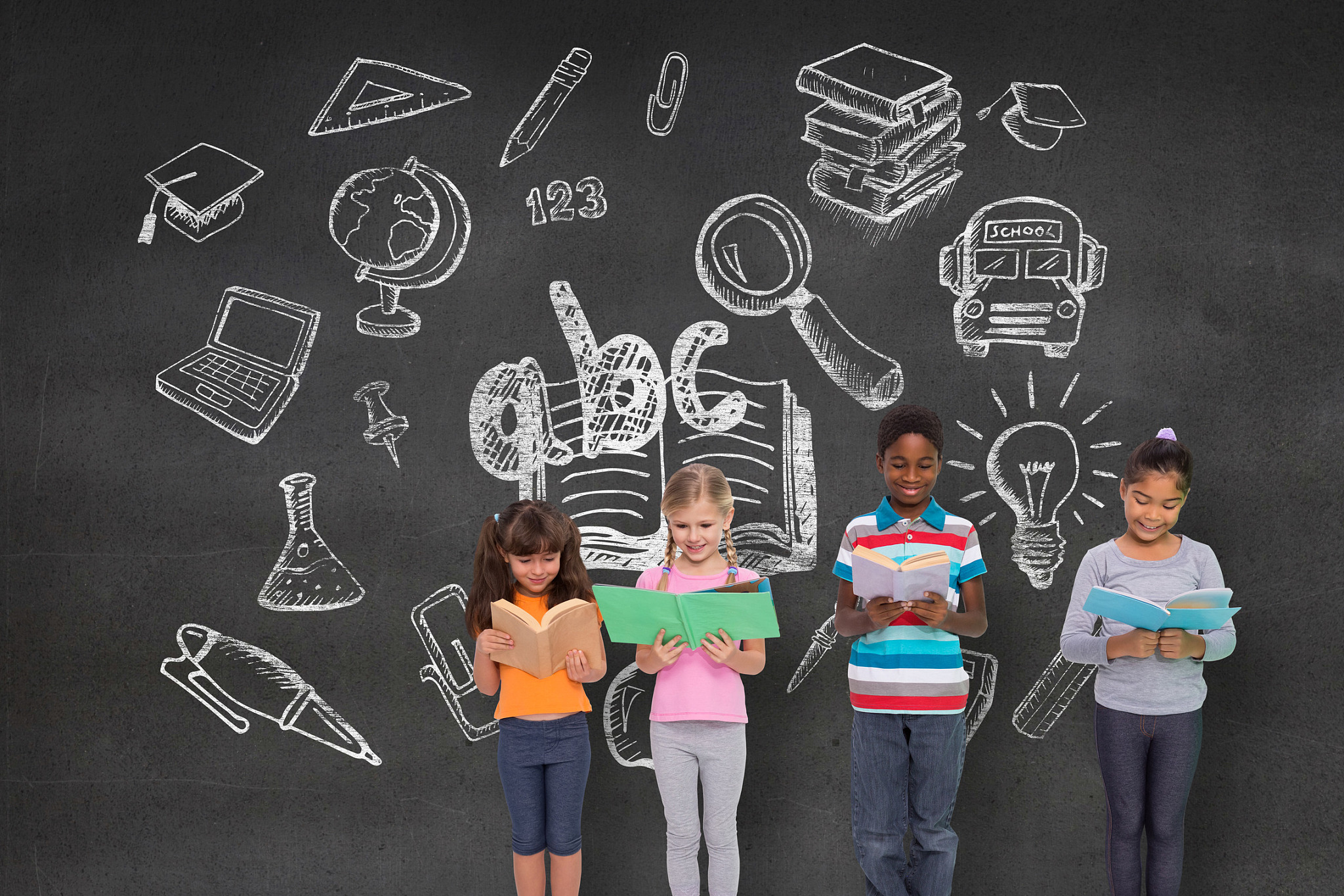 elementary pupils reading against black wall with school doodles