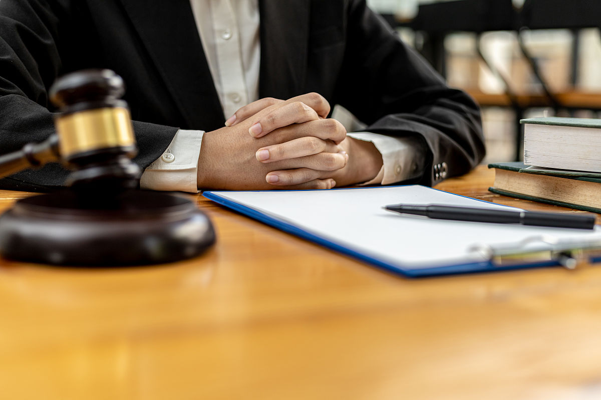 一个律师坐在他办公室的桌子上,用一把小锤子在法庭上敲打法官的桌子.