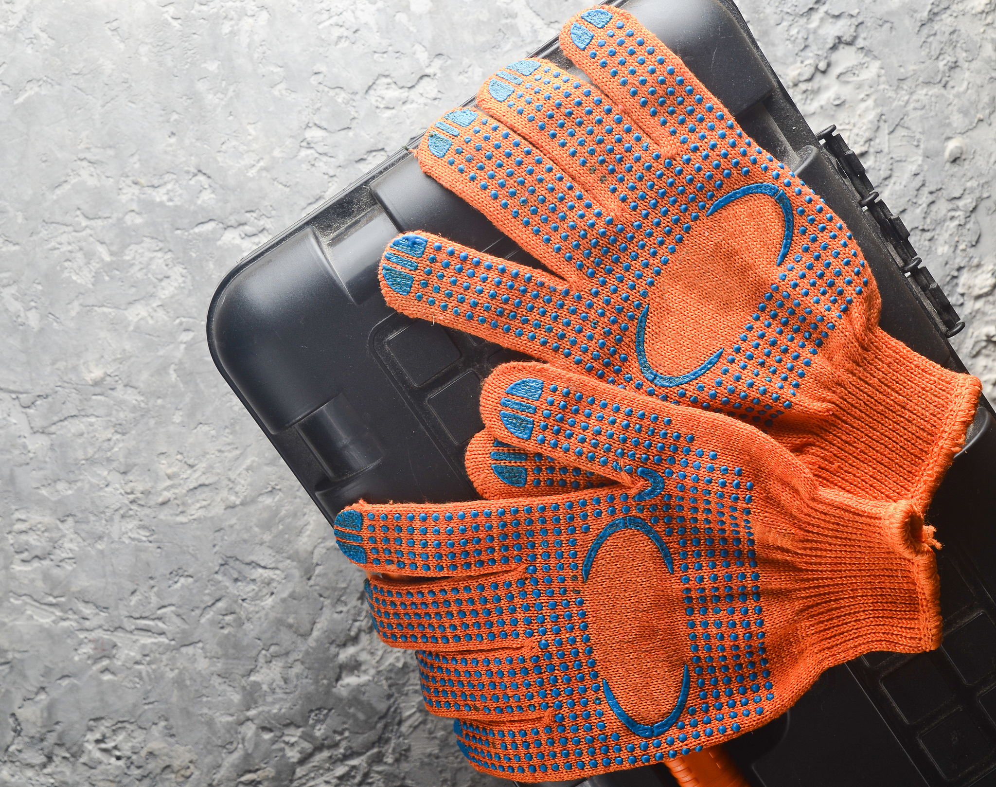 orange work gloves on a tool box on a gray concrete background. 