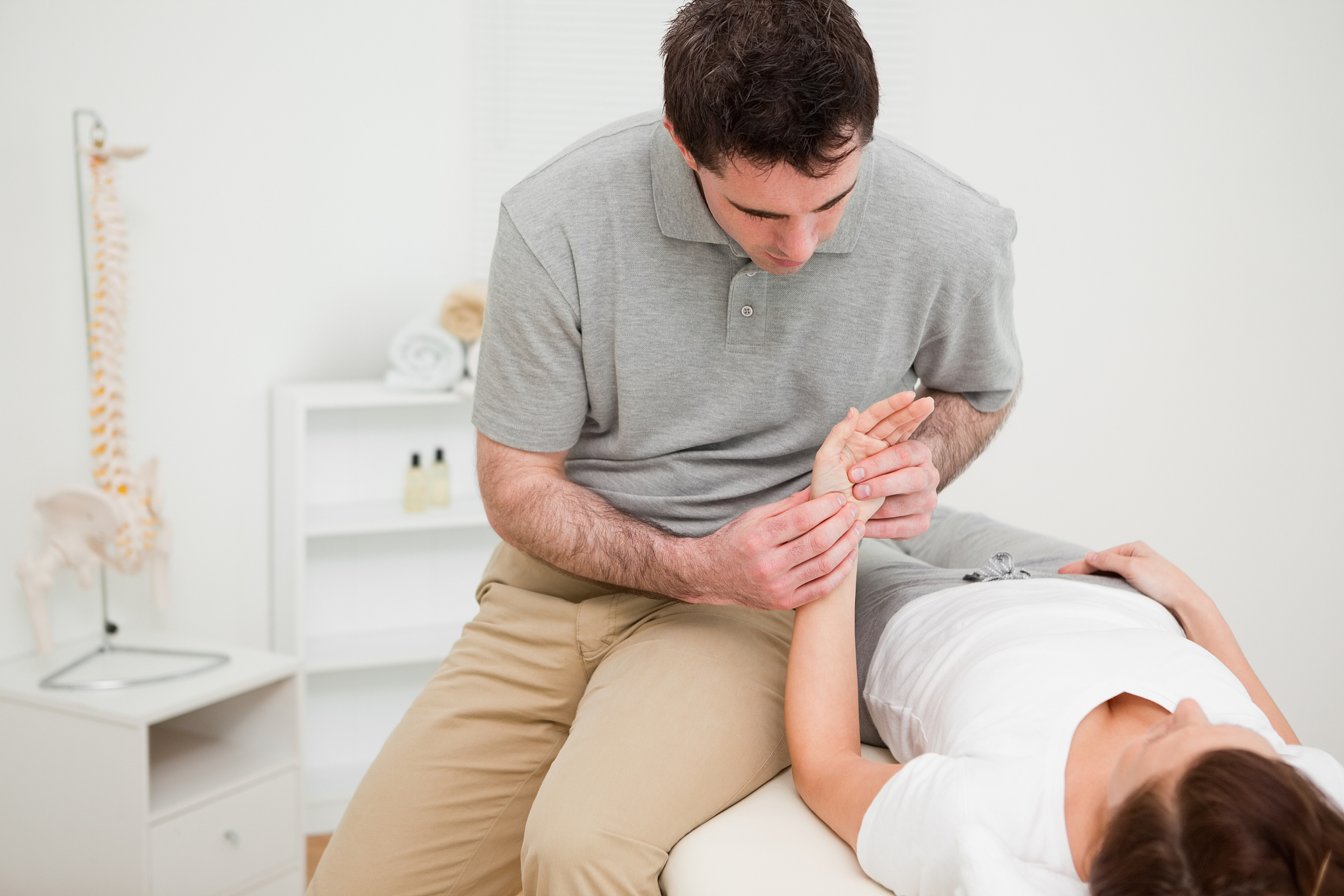 serious physiotherapist holding the hand of a woman