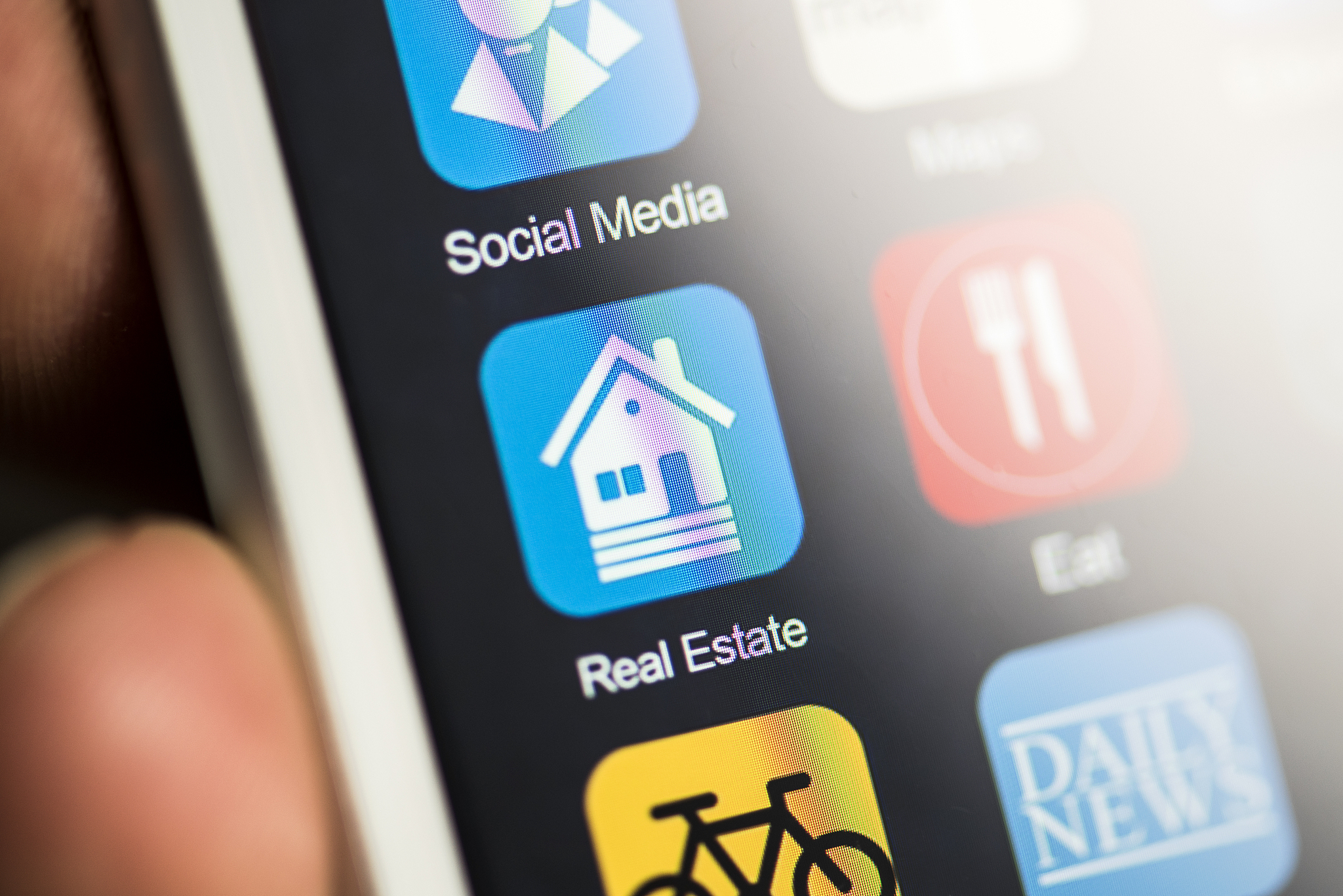 hand holding phone, real estate app on screen