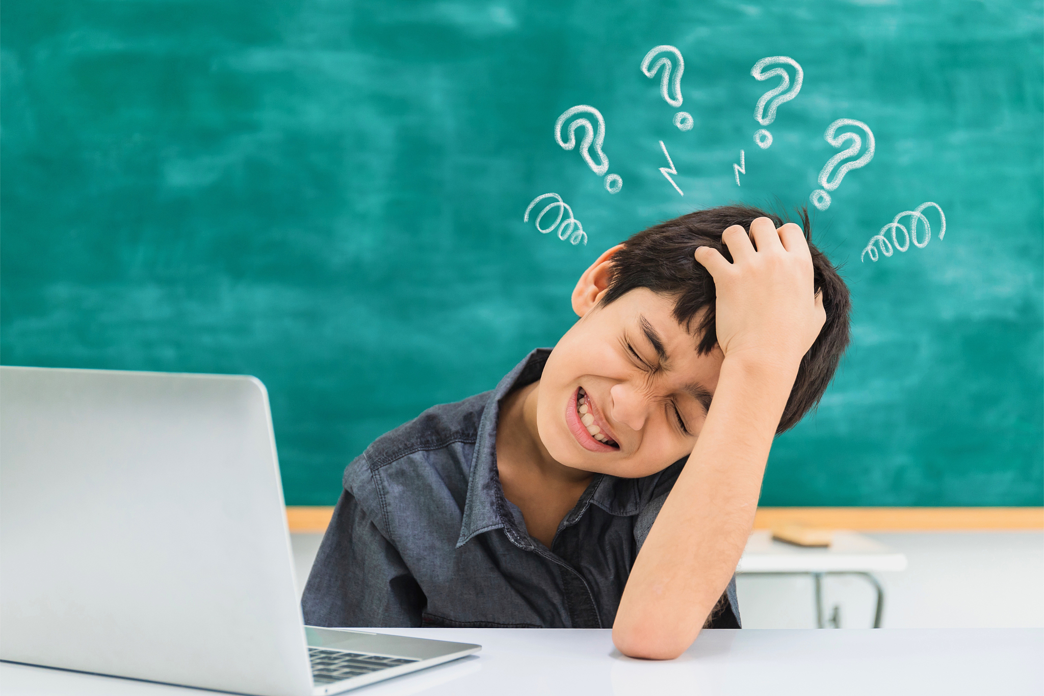 asian confused school boy using laptop on black board background