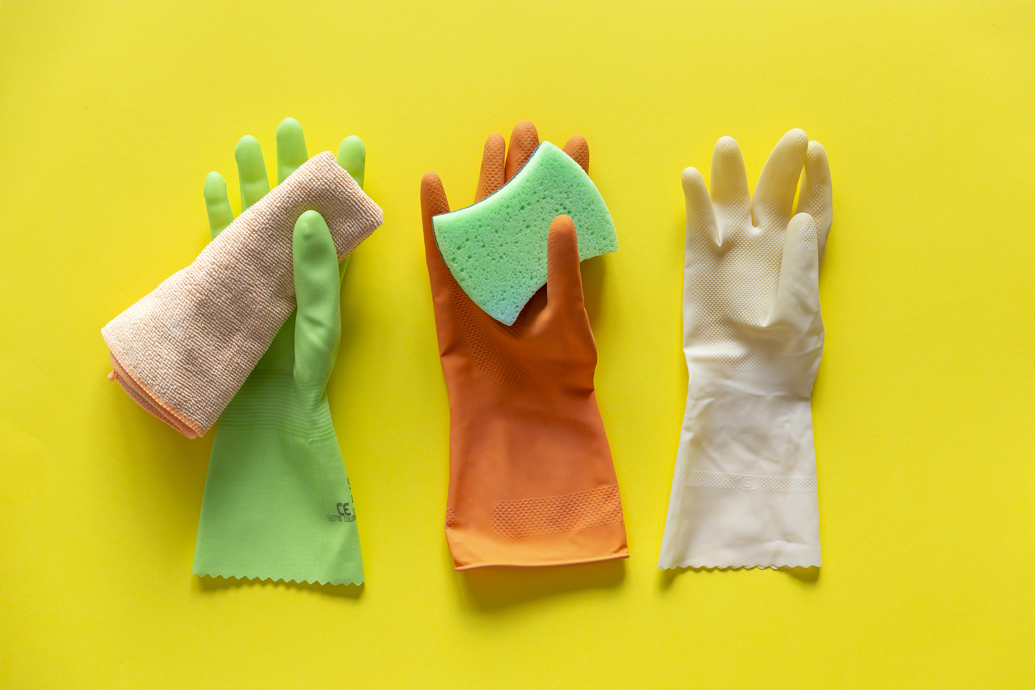 colorful washing up cleaning gloves,  rag and sponge on bright y