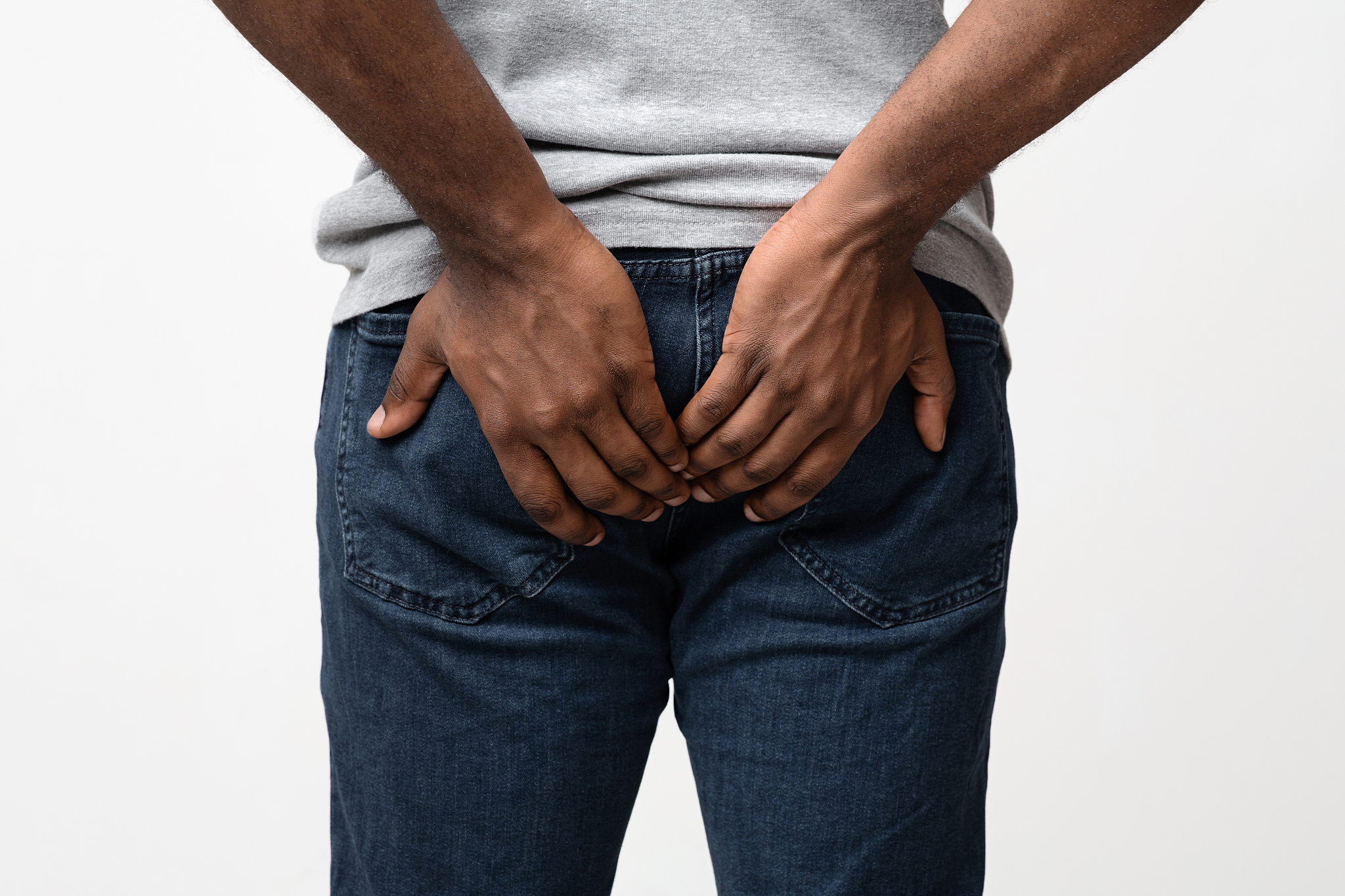 man with hemorrhoids holding his butt in pain