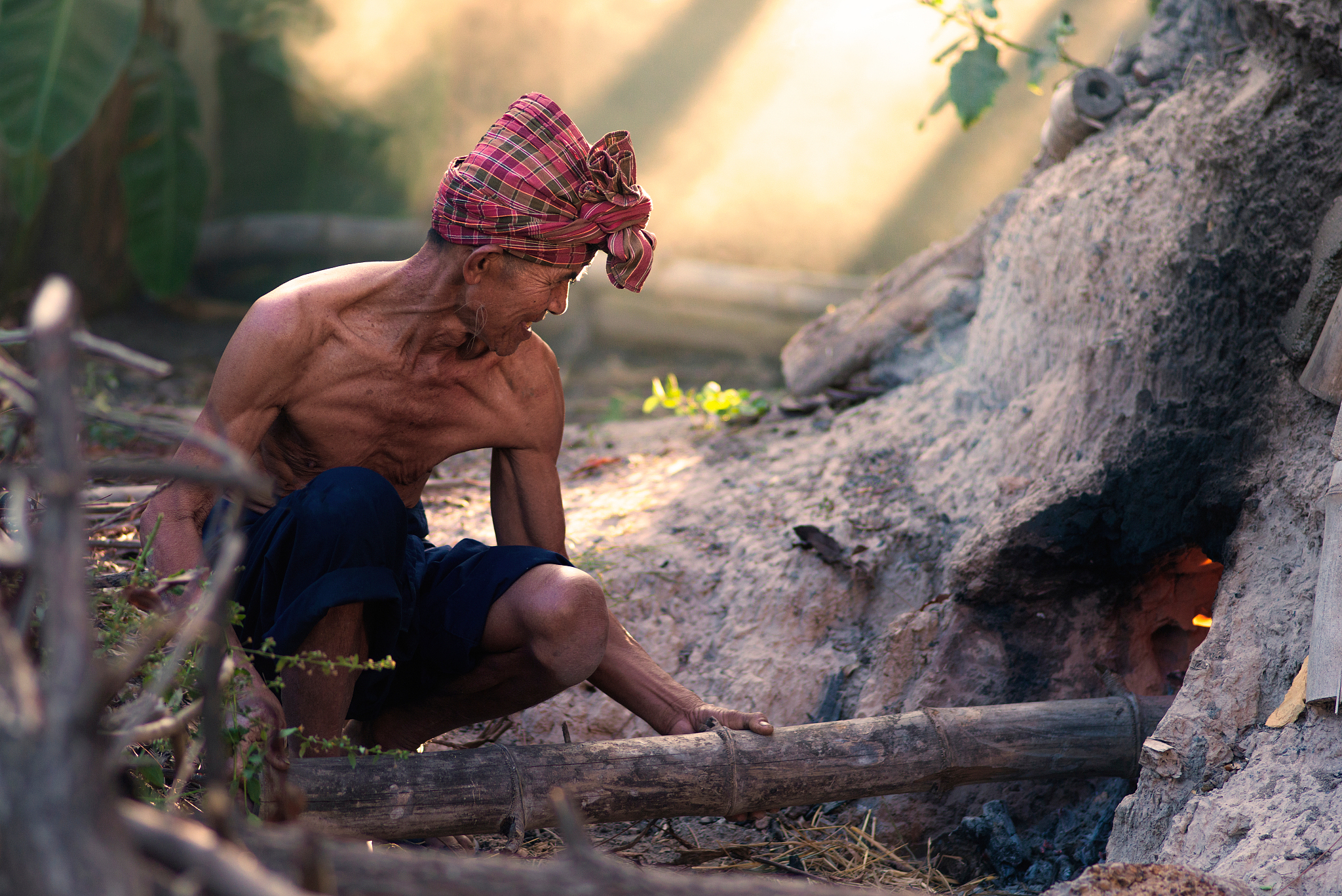 senior man burning bamboo in forest