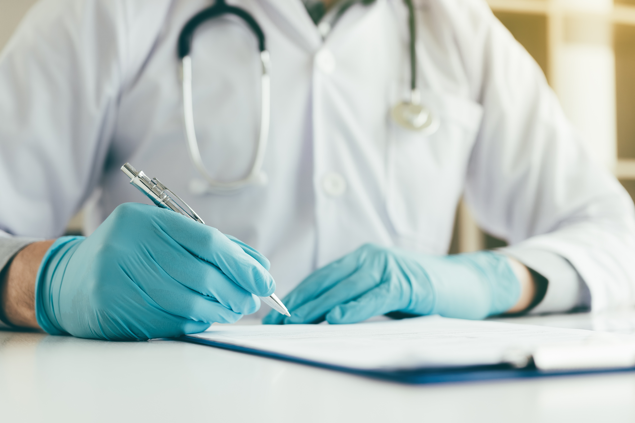 doctor is writing a summary report on table in his lab.